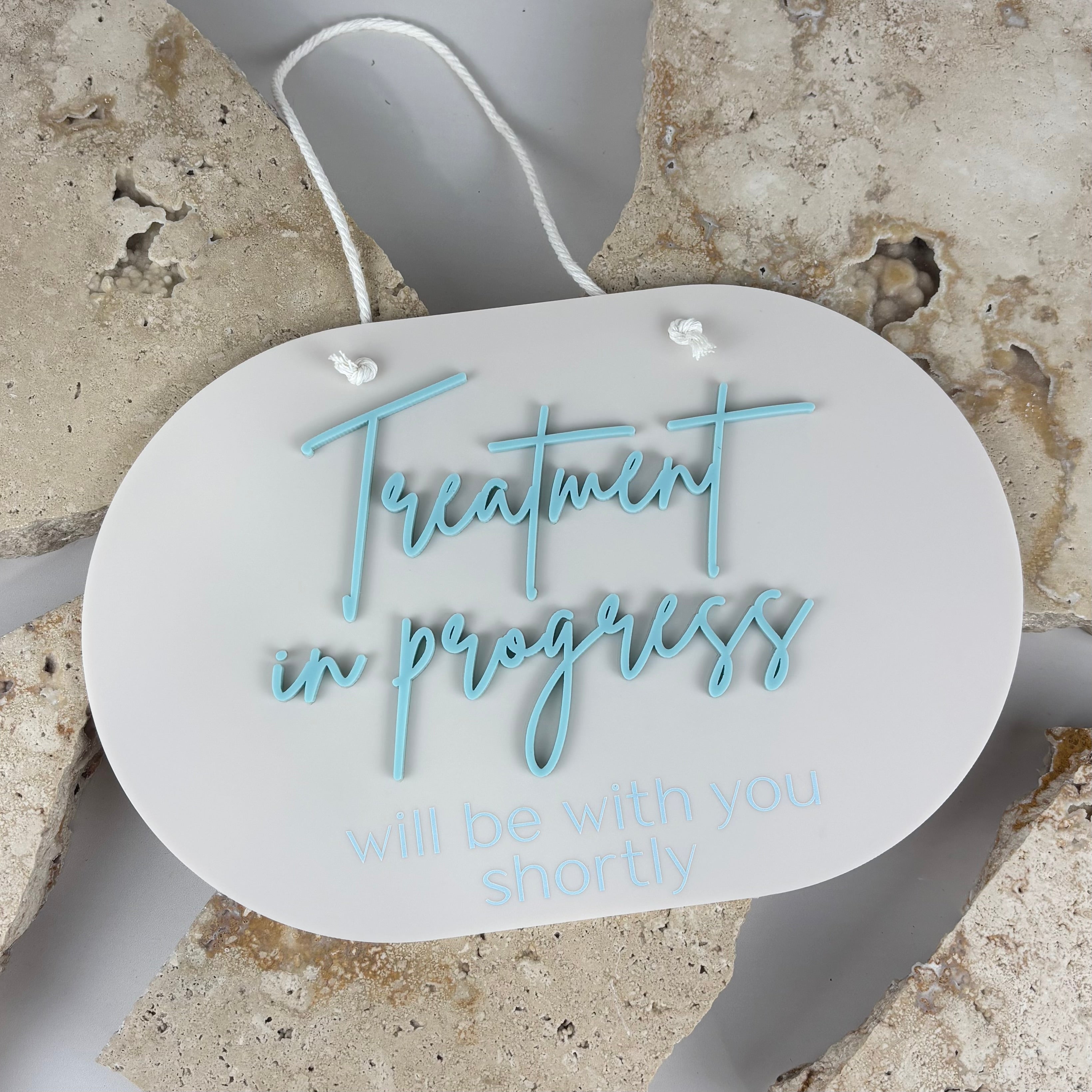 Reversible oval acrylic door sign reading “Treatment in progress will be with you shortly”, professional salon or clinic privacy sign with rope hanger
