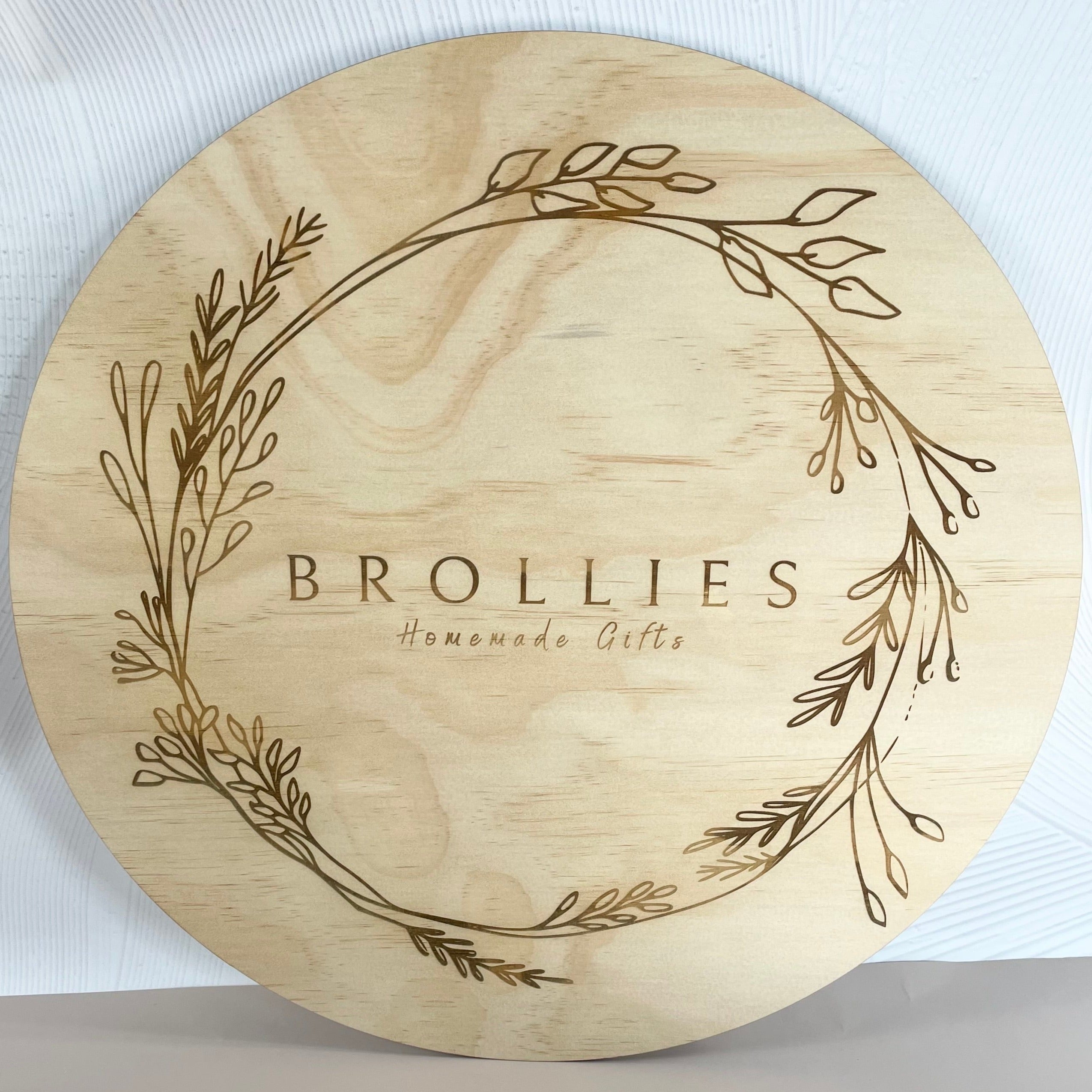 Brollies timber sign with wreath engraving, custom round wood sign with delicate botanical design and wedding business name.