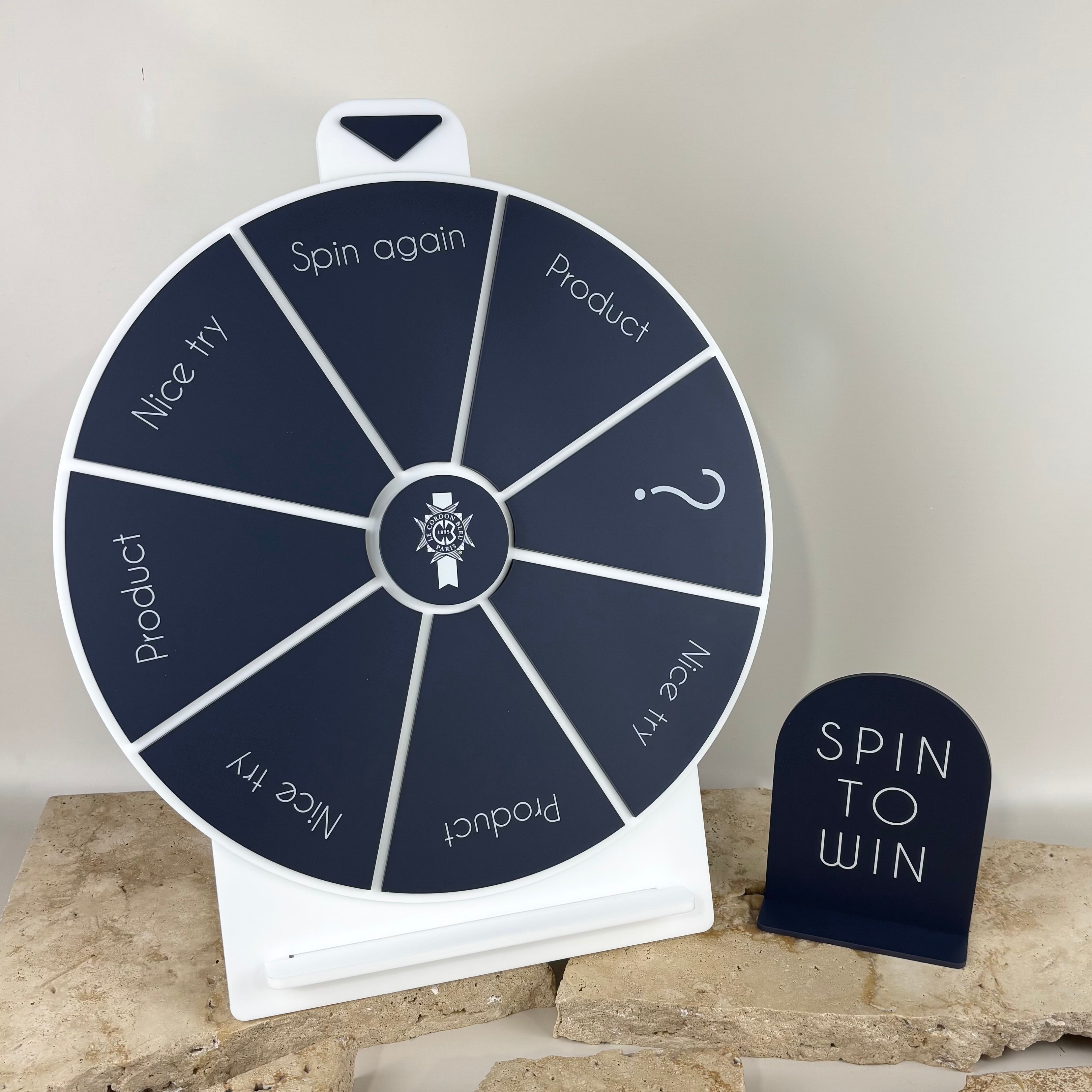 Custom acrylic spin the wheel prize game with “Spin to Win” display sign, branded promotional wheel used by businesses, retail stores and market stalls to attract customers, run giveaways and increase engagement at events or in-store promotions.