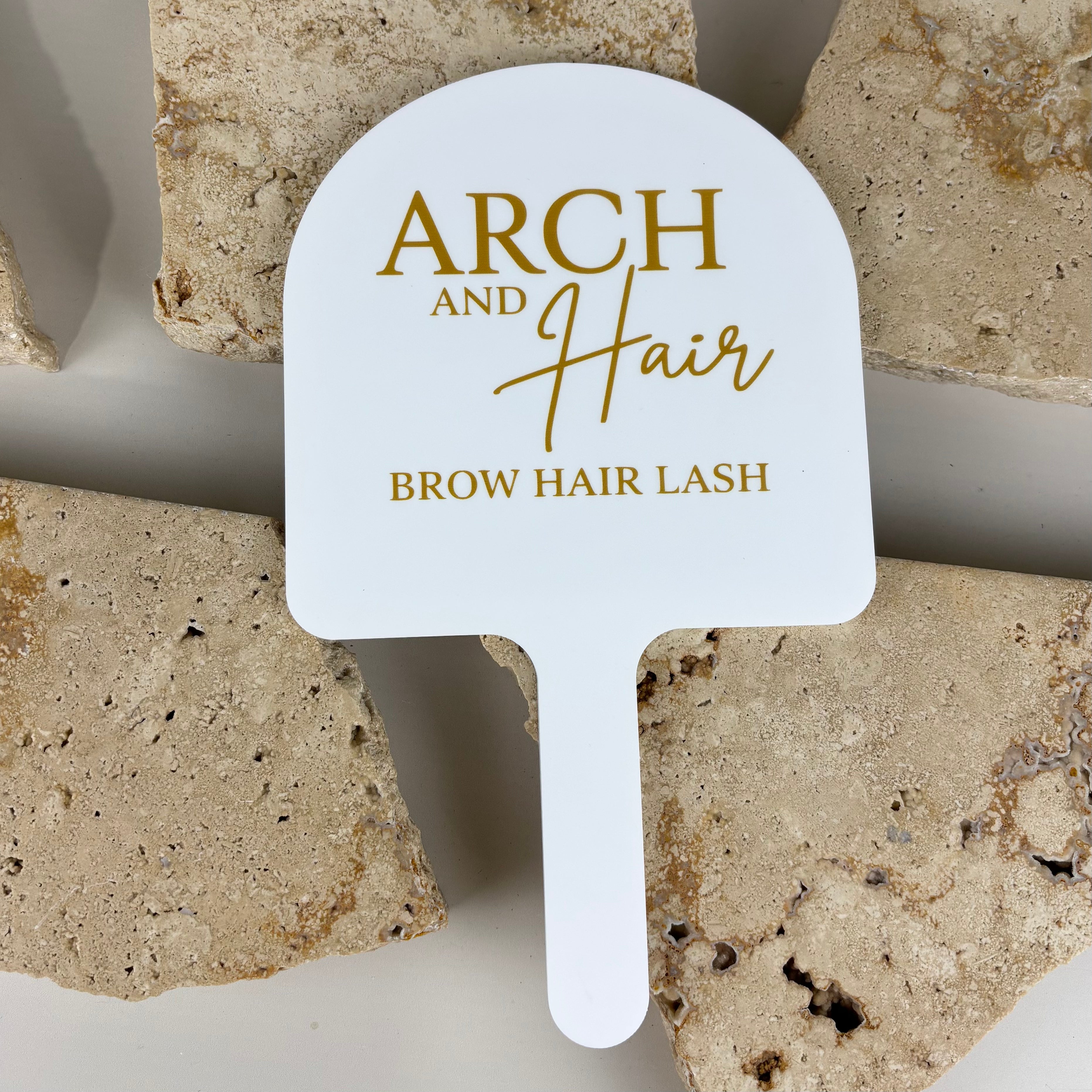 White acrylic branded handheld mirror with gold logo, premium custom hand mirror for brow, lash and hair studios, professional salon mirror designed for client consultations, treatments and service reveals.