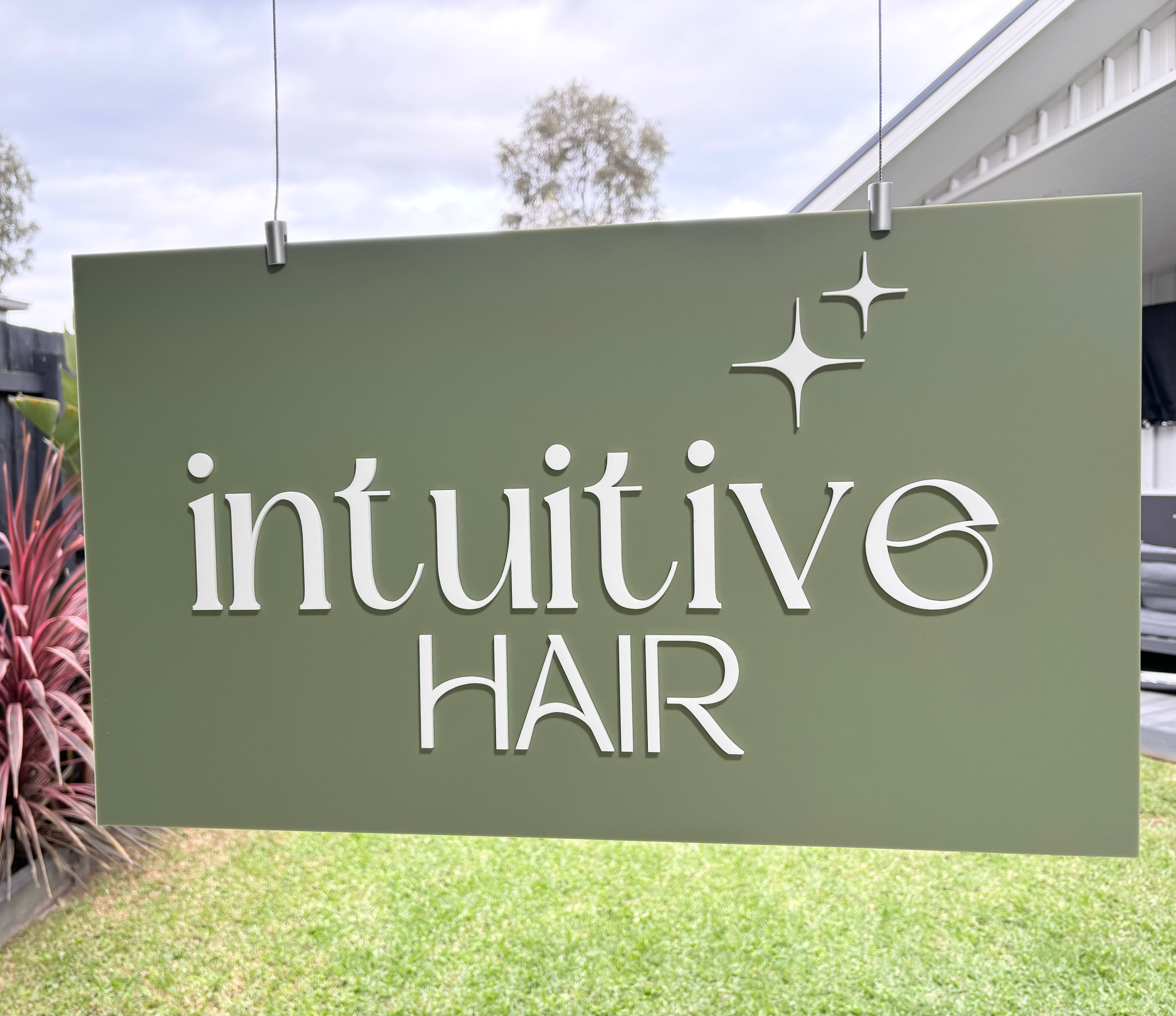 Custom acrylic hanging sign with Intuitive Hair logo installed indoors