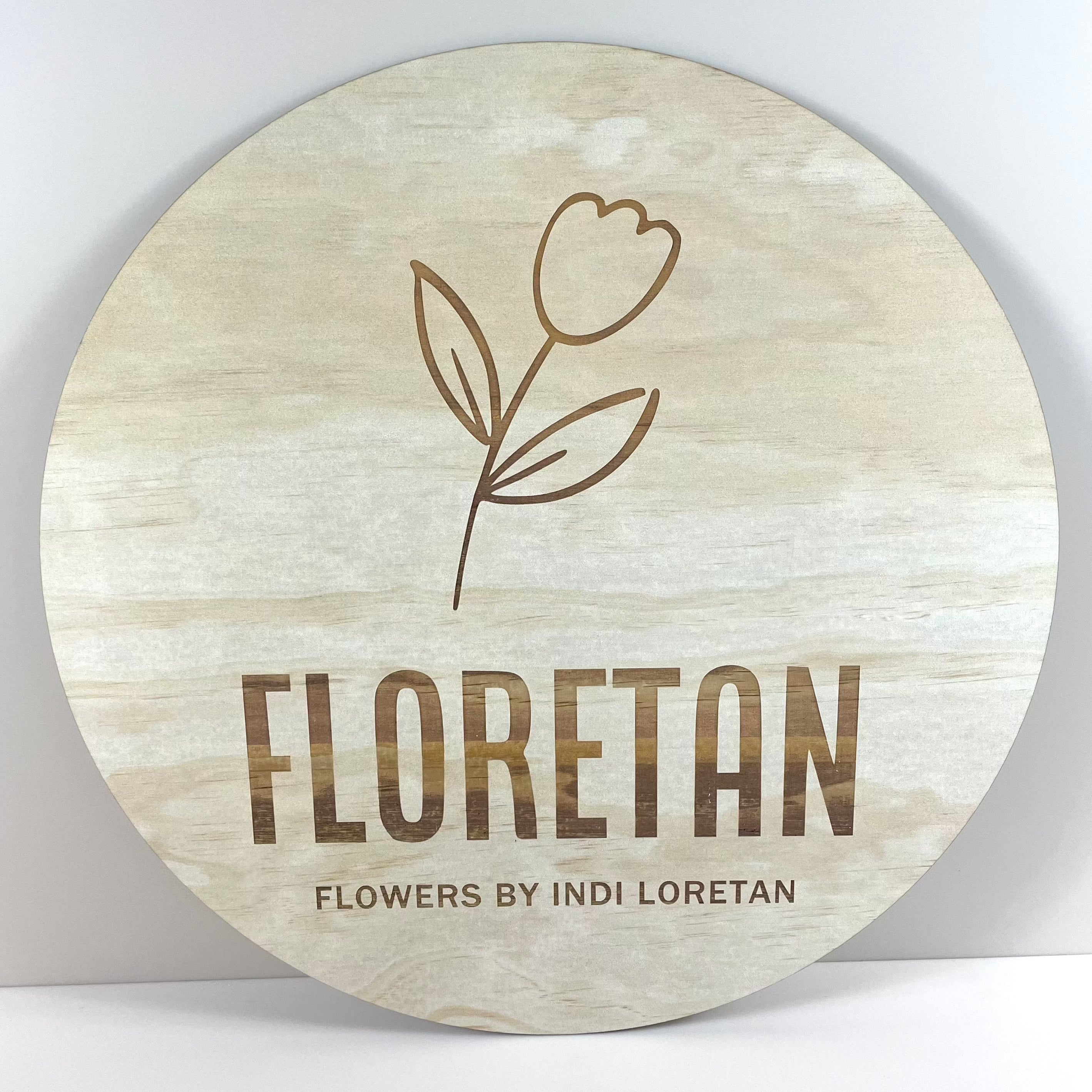 Floretan floral engraved timber sign – light wood round sign with simple tulip logo and custom flower business branding.