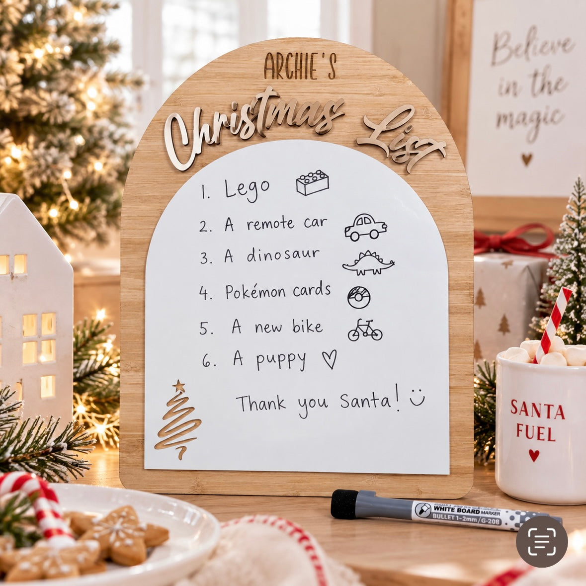 Personalised wooden Christmas wish list board for Archie, displayed in a bright modern Christmas setting with a child writing their Christmas list for Santa.