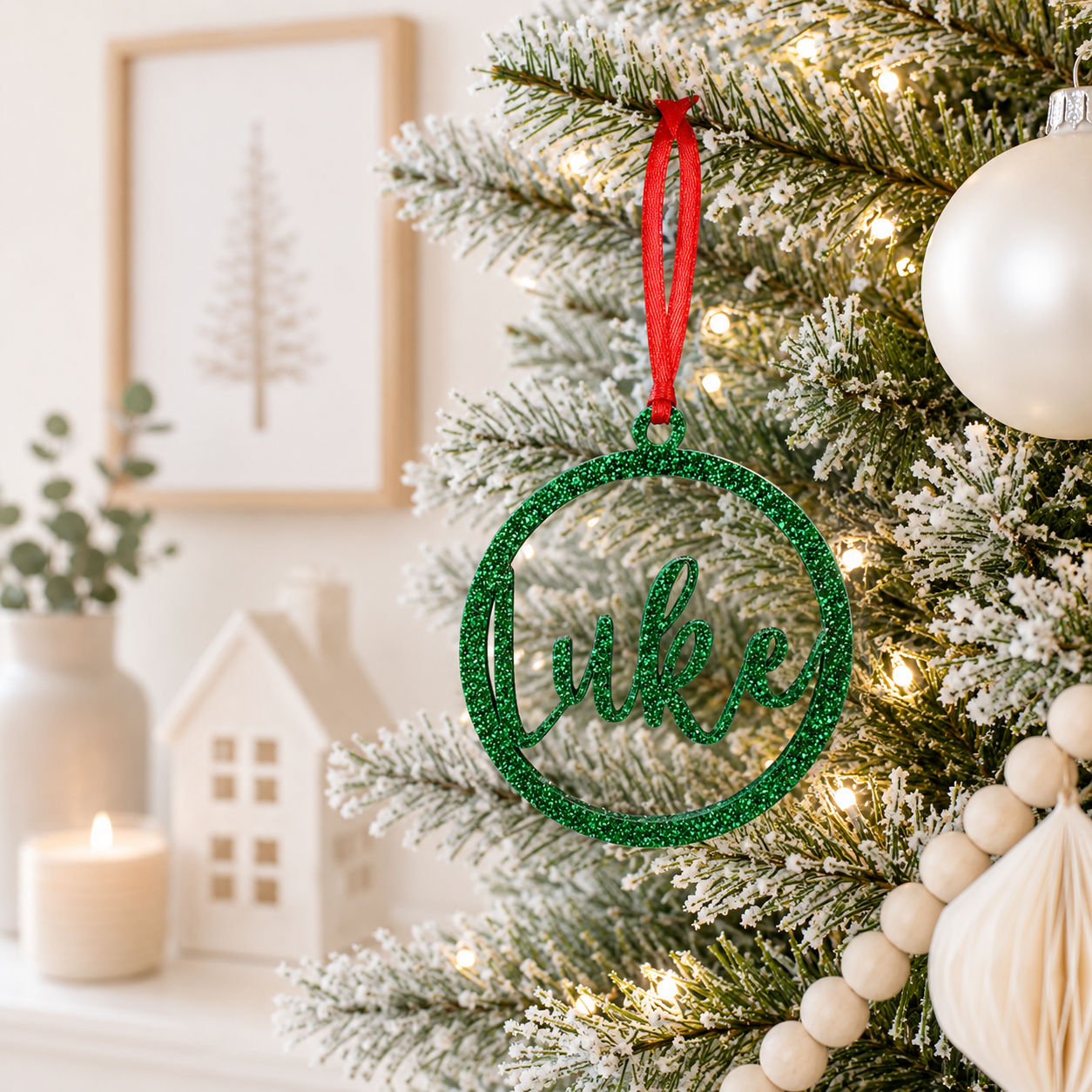 Personalised green glitter acrylic Christmas bauble with custom script name, hanging on a modern frosted Christmas tree.