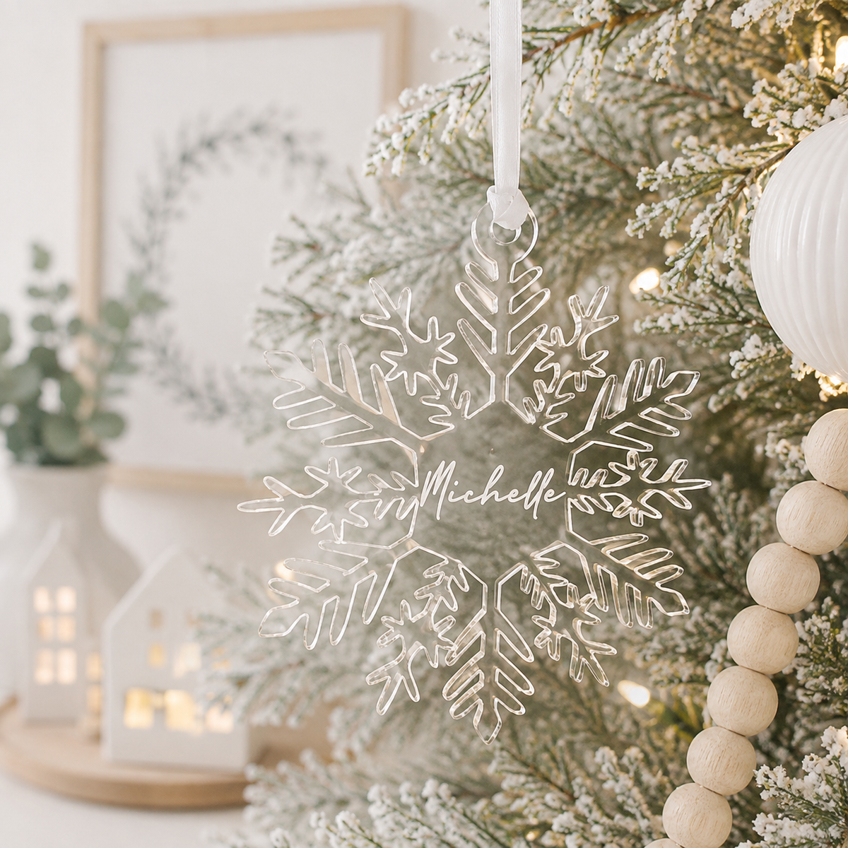 Personalised clear acrylic snowflake Christmas bauble with custom engraved name, hanging on a modern frosted Christmas tree.