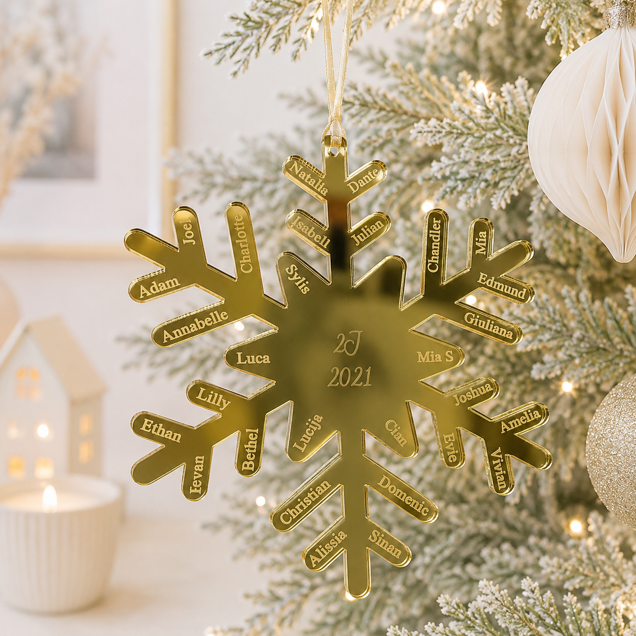 Personalised gold mirror acrylic snowflake Christmas bauble with custom engraved names and year, hanging on a modern frosted Christmas tree.