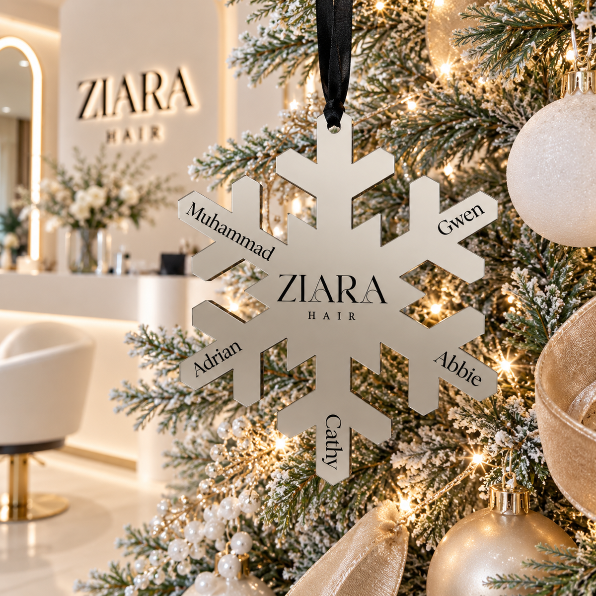 Personalised mirror acrylic snowflake Christmas bauble with business logo and staff names, hanging on a modern Christmas tree in a hair salon.