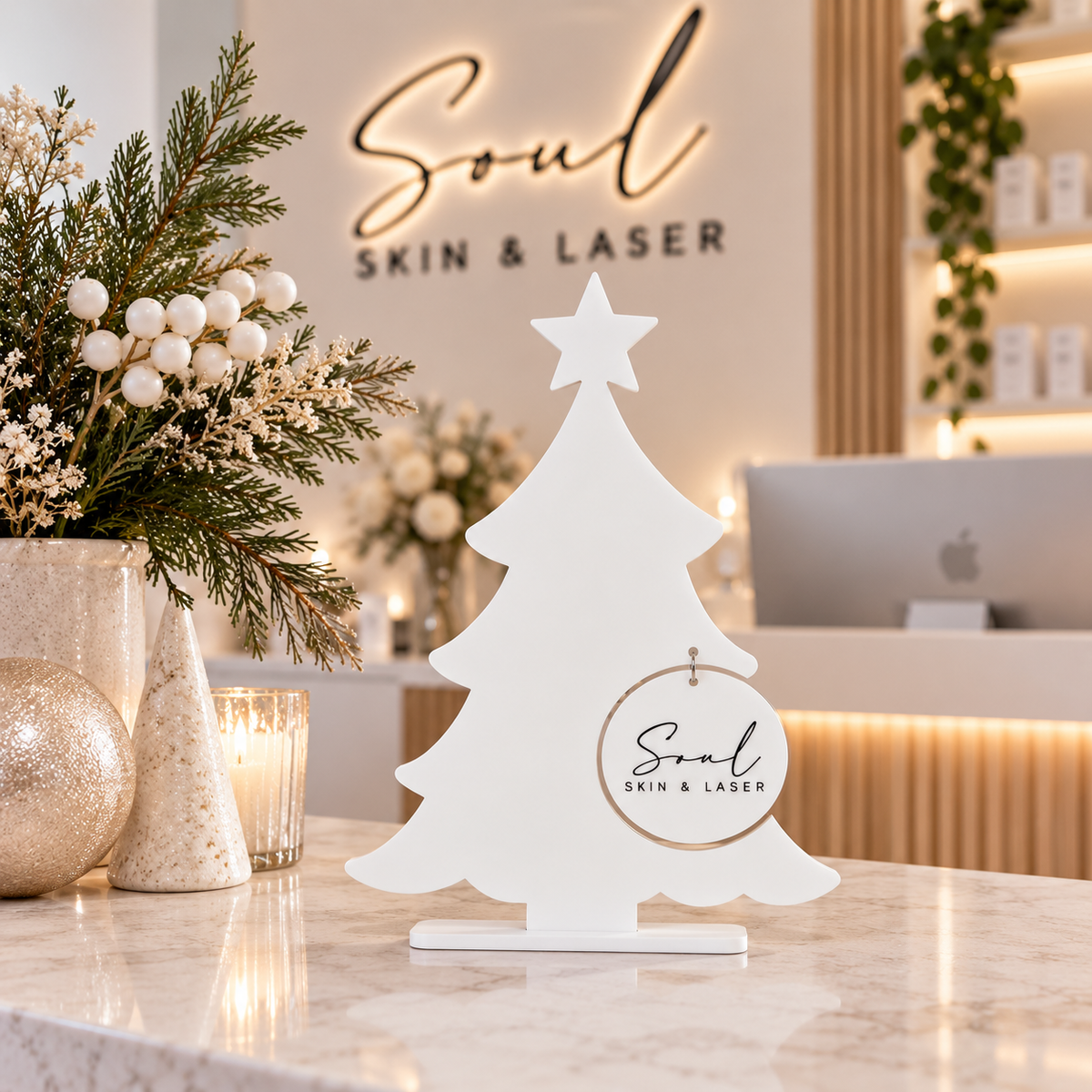 Custom business Christmas tree display with Soul Skin & Laser logo, styled on a modern beauty salon reception desk with festive Christmas décor.