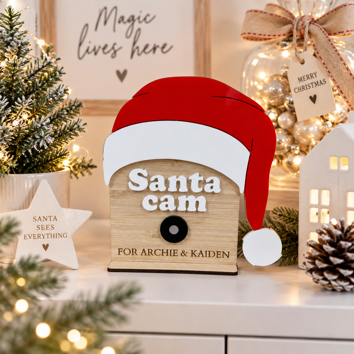 Personalised wooden Santa cam Christmas decoration for Archie and Kaiden, displayed in a bright modern Christmas setting with festive lights and decorations.