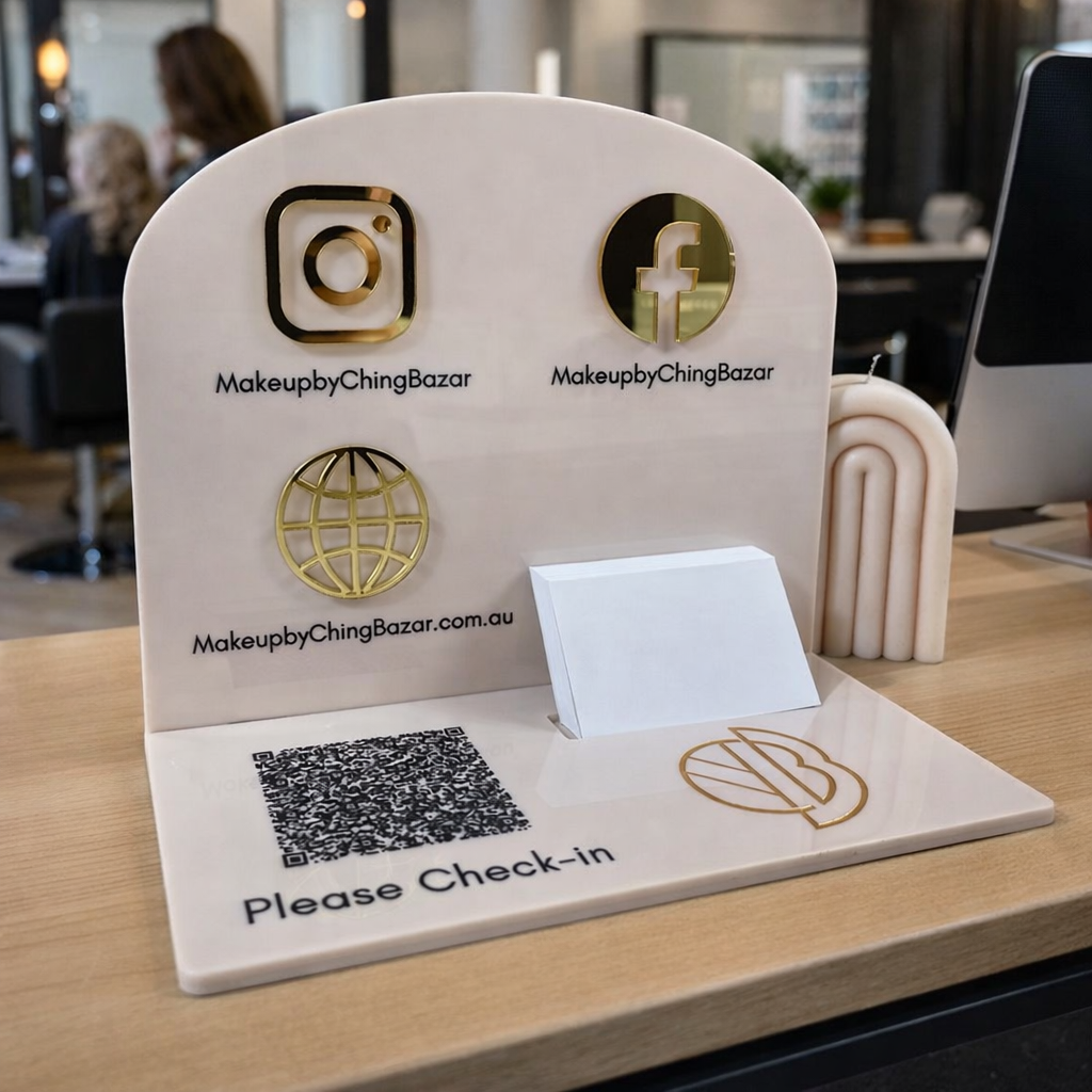 Custom acrylic NFC check-in stand displayed on a hair salon reception desk, featuring QR code check-in, Instagram and Facebook icons, website URL and business card holder, designed for hairdressers and beauty salons in Australia