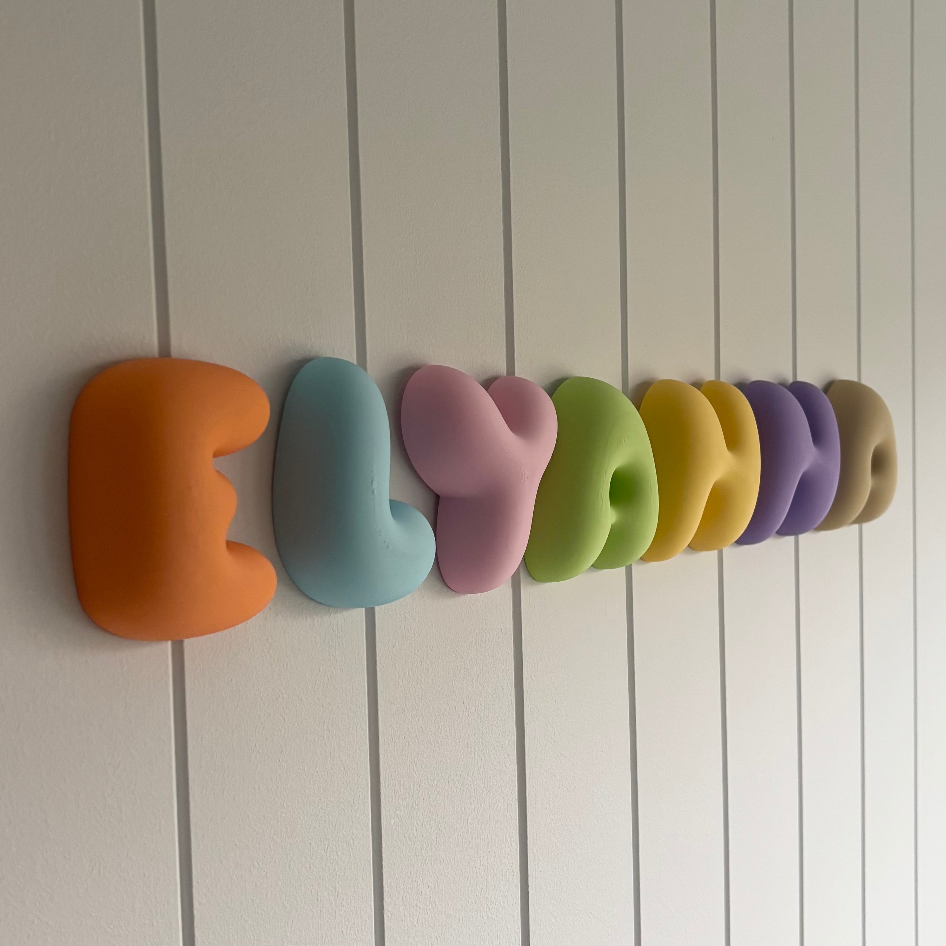 Colourful 3D printed bubble letters spelling “ELYANNA”, featuring soft rounded lettering in a mix of bright pastel colours for personalised bedroom and wall decor.