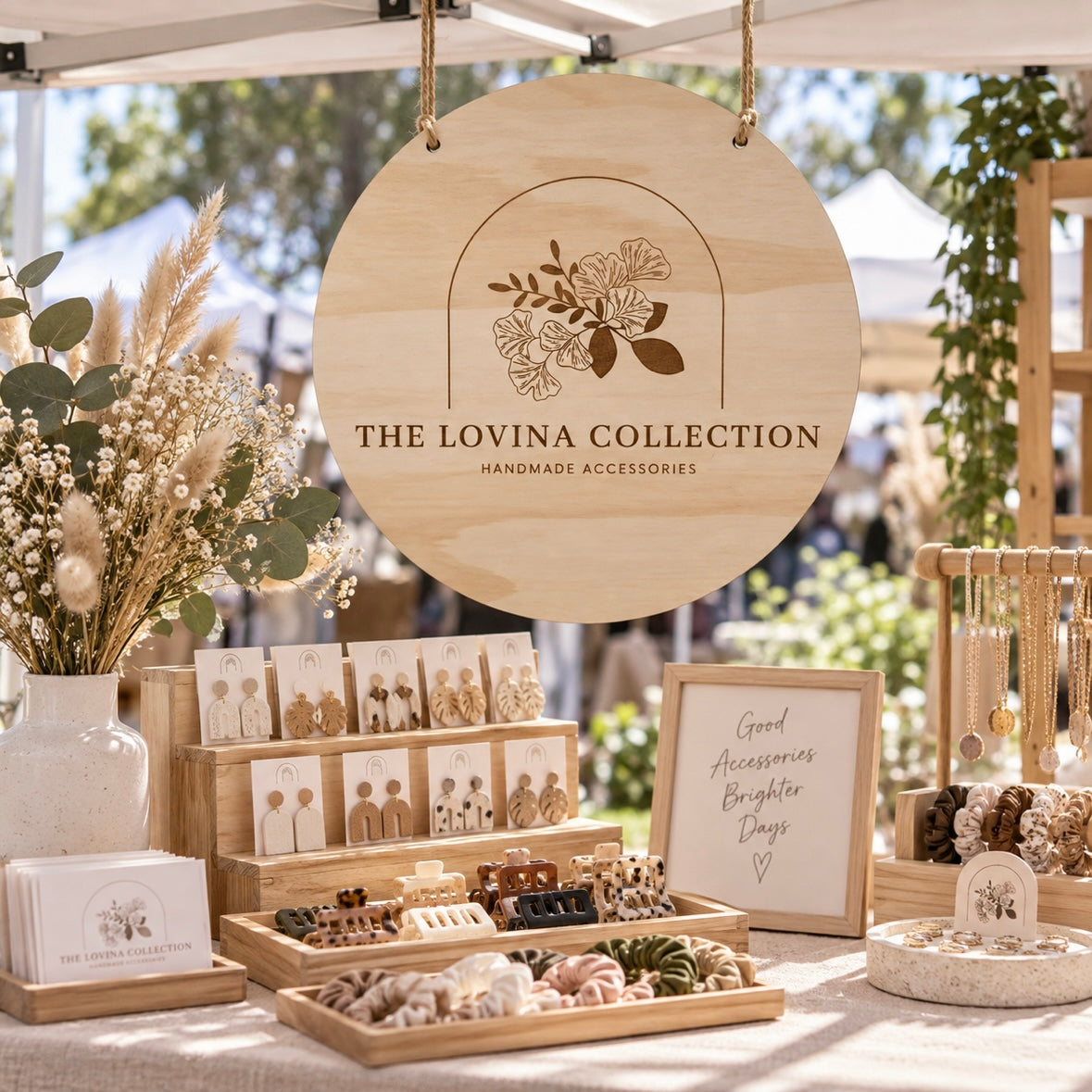 Custom round timber business sign with engraved floral logo for The Lovina Collection, hanging at a handmade accessories market stall.