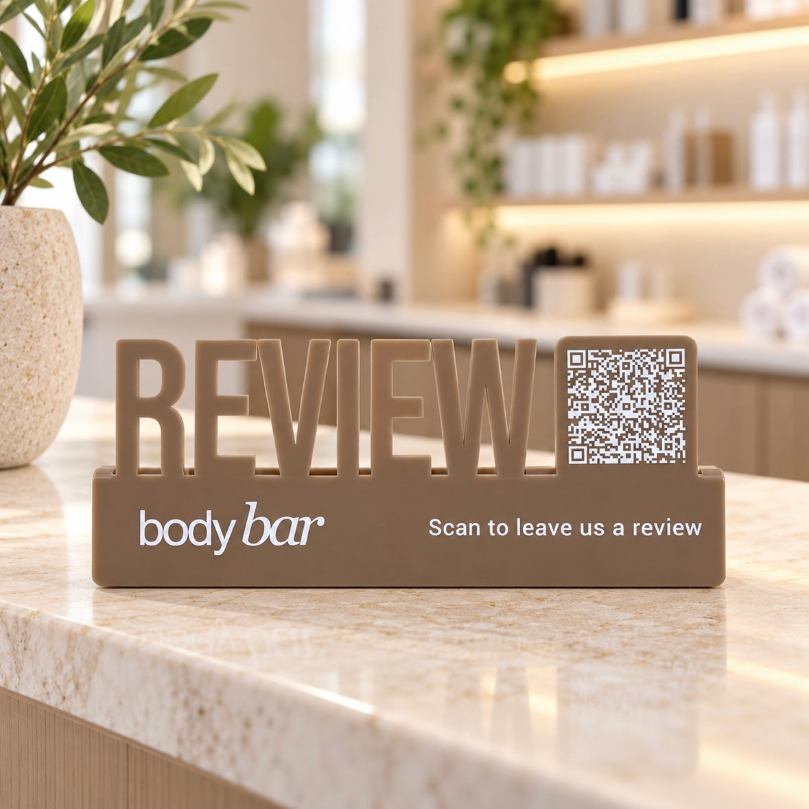 Custom acrylic Google review sign with QR code and raised REVIEW lettering, displayed on a modern salon or beauty reception counter.