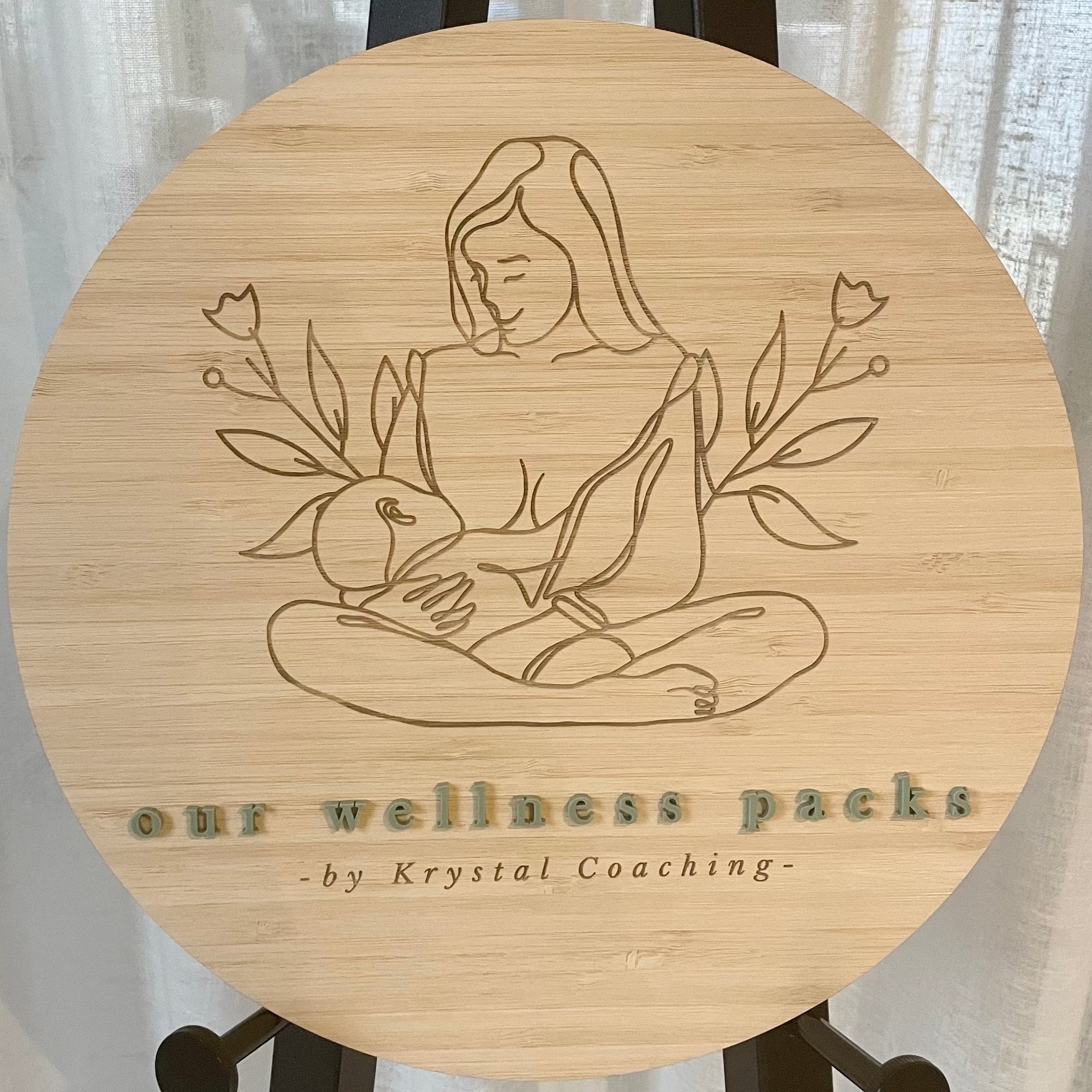Our Wellness Packs engraved bamboo sign with seated yoga figure