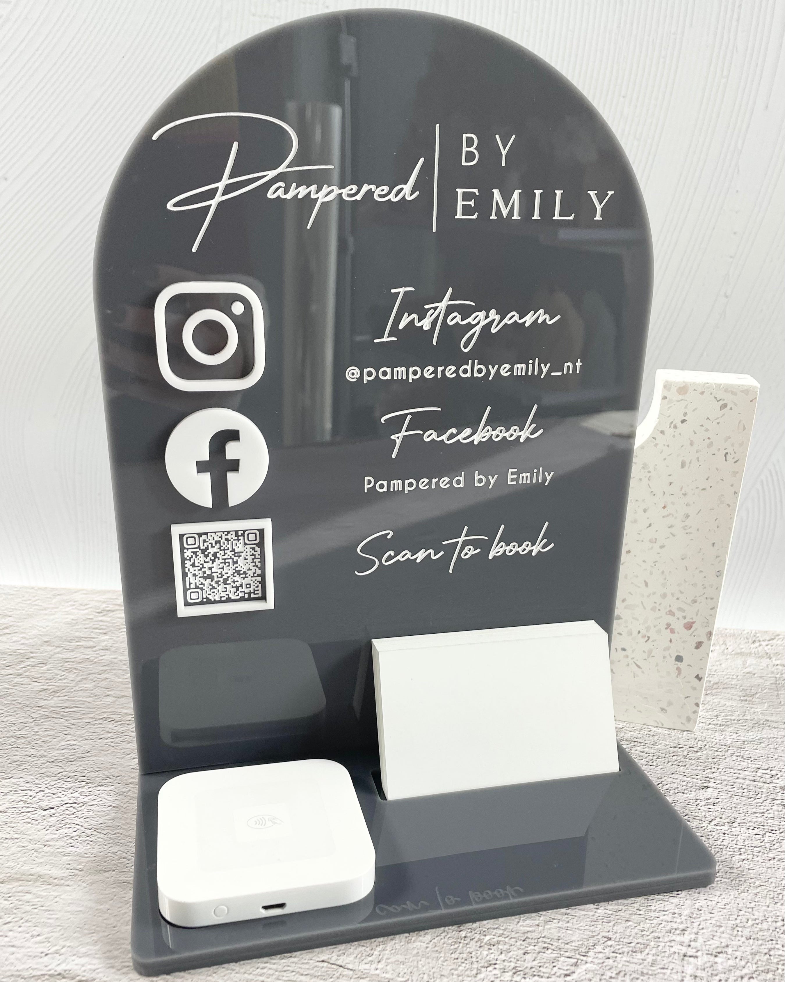 Grey branded stand with Instagram and Facebook icons with qr booking code, card and square reader
