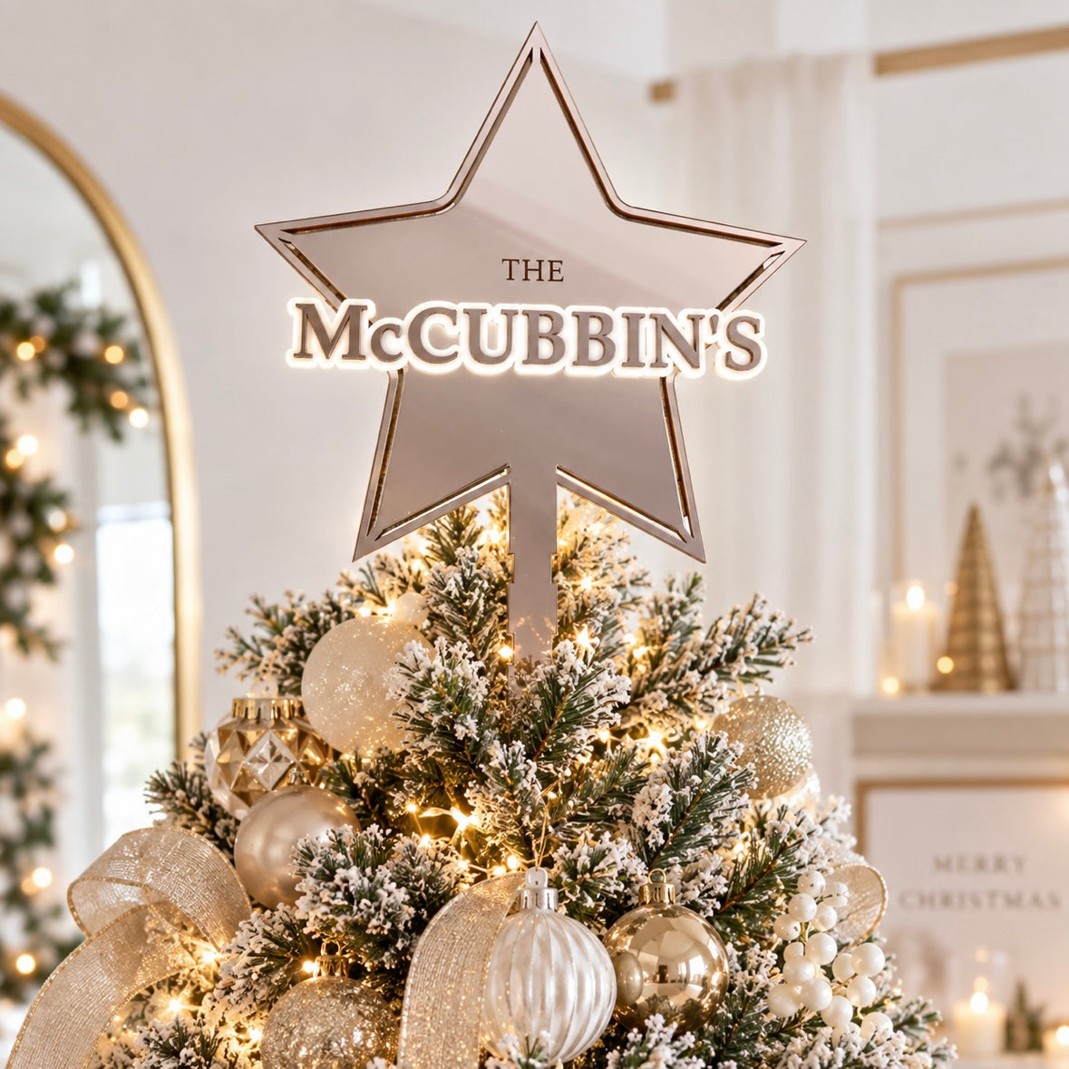 Personalised family Christmas tree topper with The McCubbin’s name in mirror acrylic, displayed on a light modern Christmas tree with gold and white decorations.