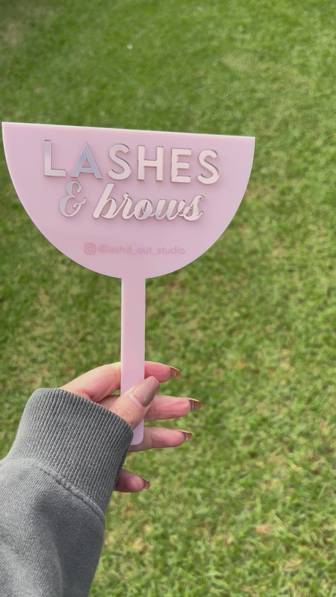 Close up of pink custom 3D face shield with Lashes and Brows branding outdoors video