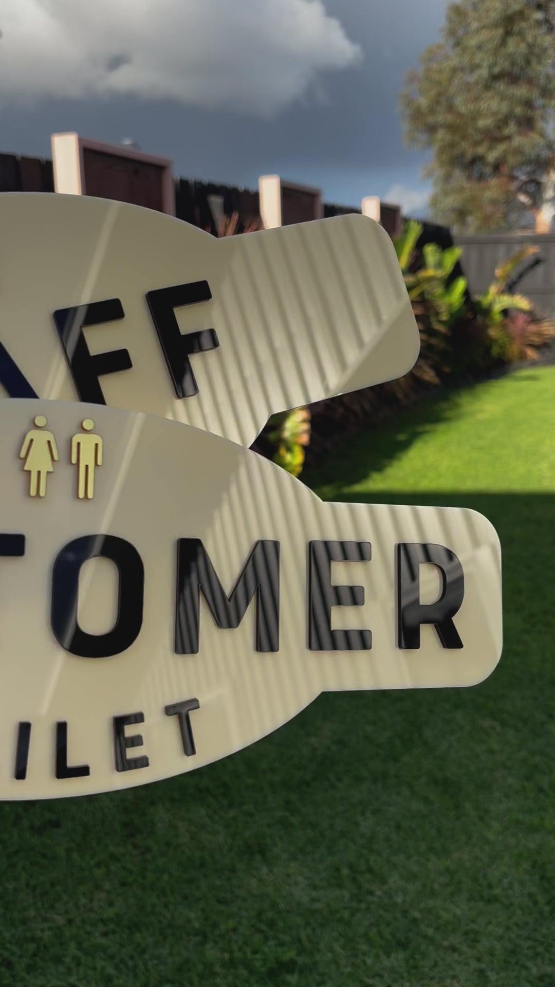 Close‑up of cream acrylic staff and customer toilet signs with bold black lettering displayed outdoors. Video