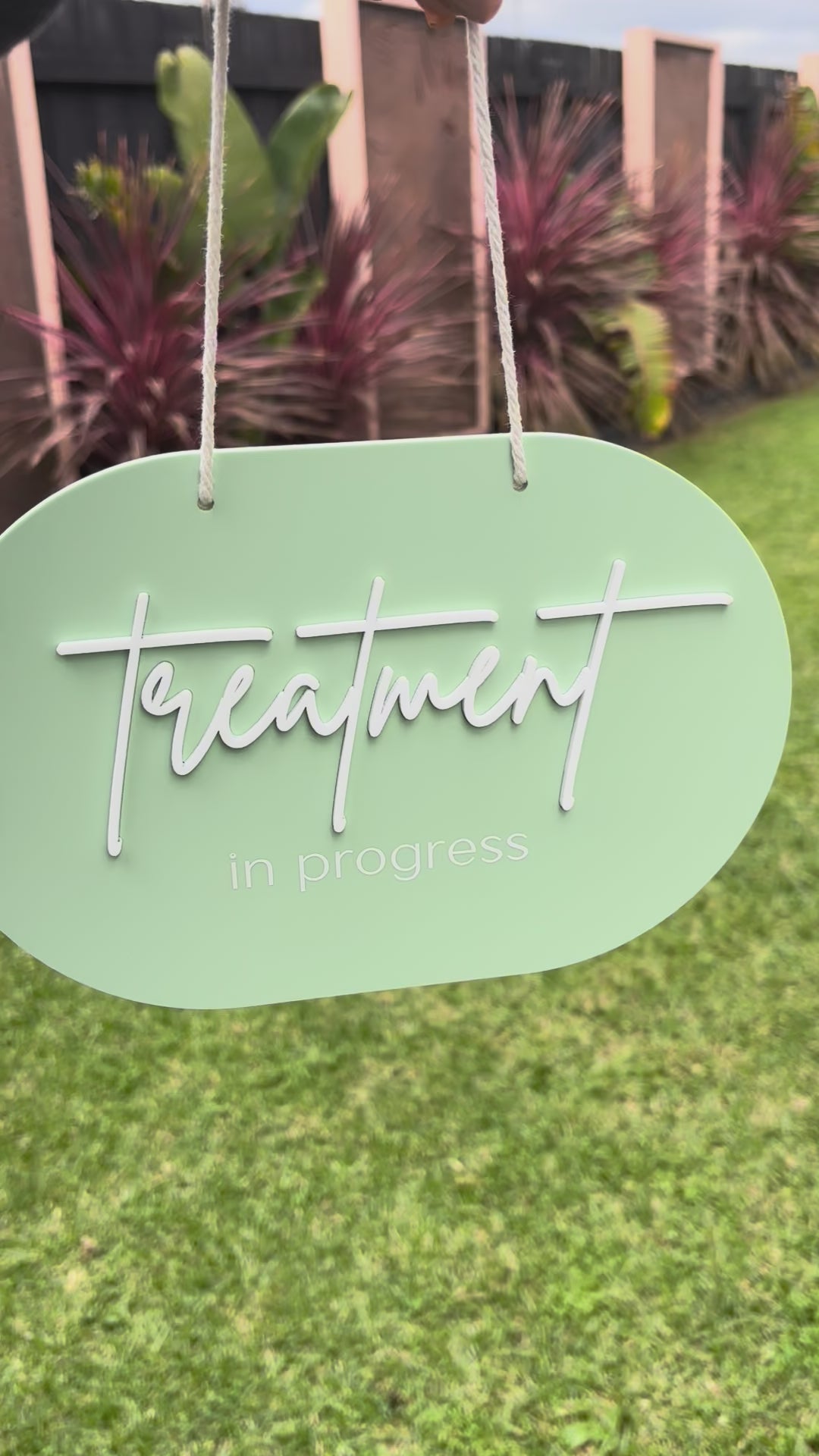 Mint green treatment in progress salon door sign shown outdoors with hanging cord. Video