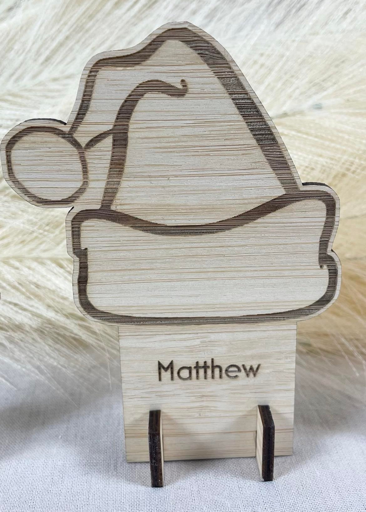 Personalised wooden Christmas place card engraved with Santa hat design for festive dinners