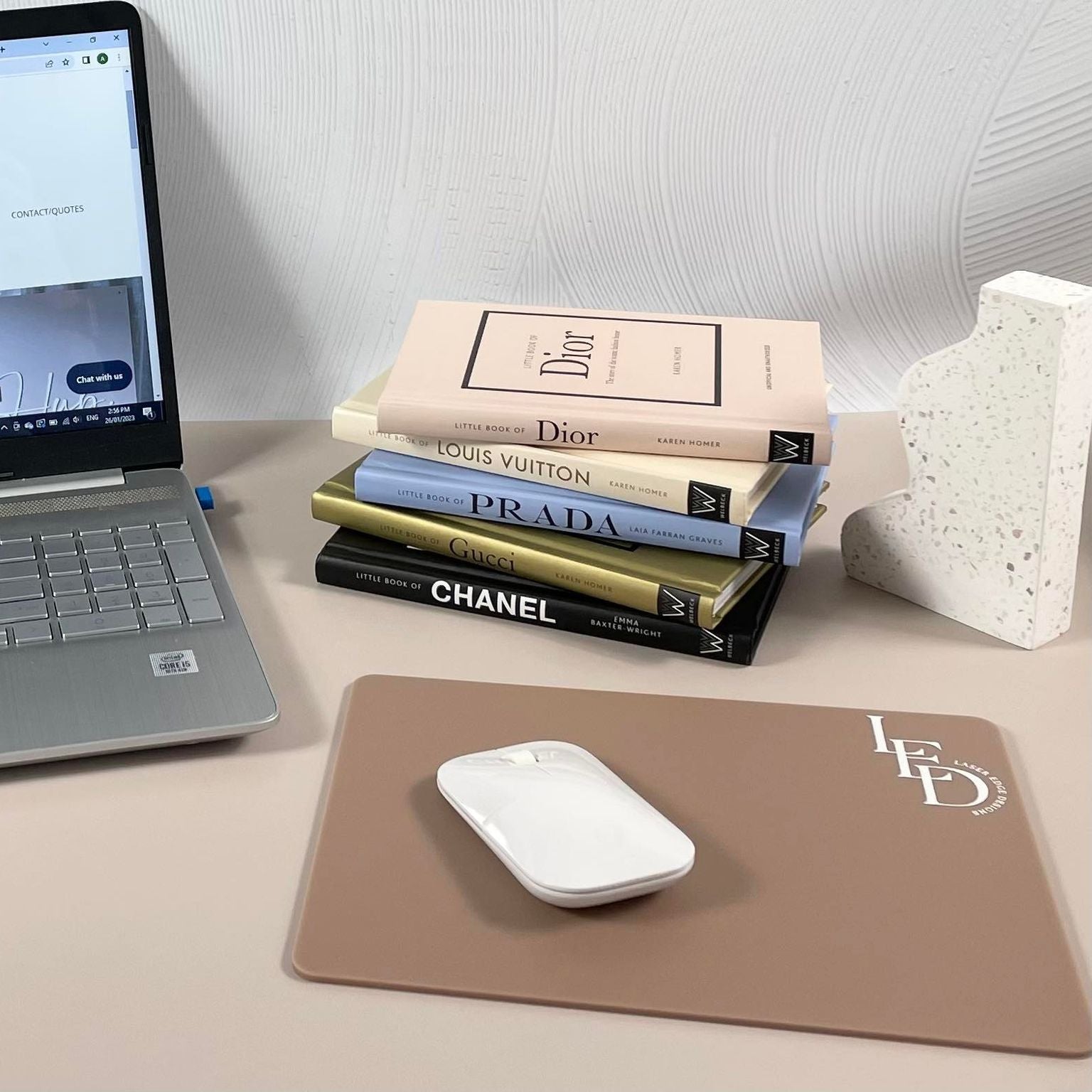 Branded mouse pad with company logo beside laptop and books