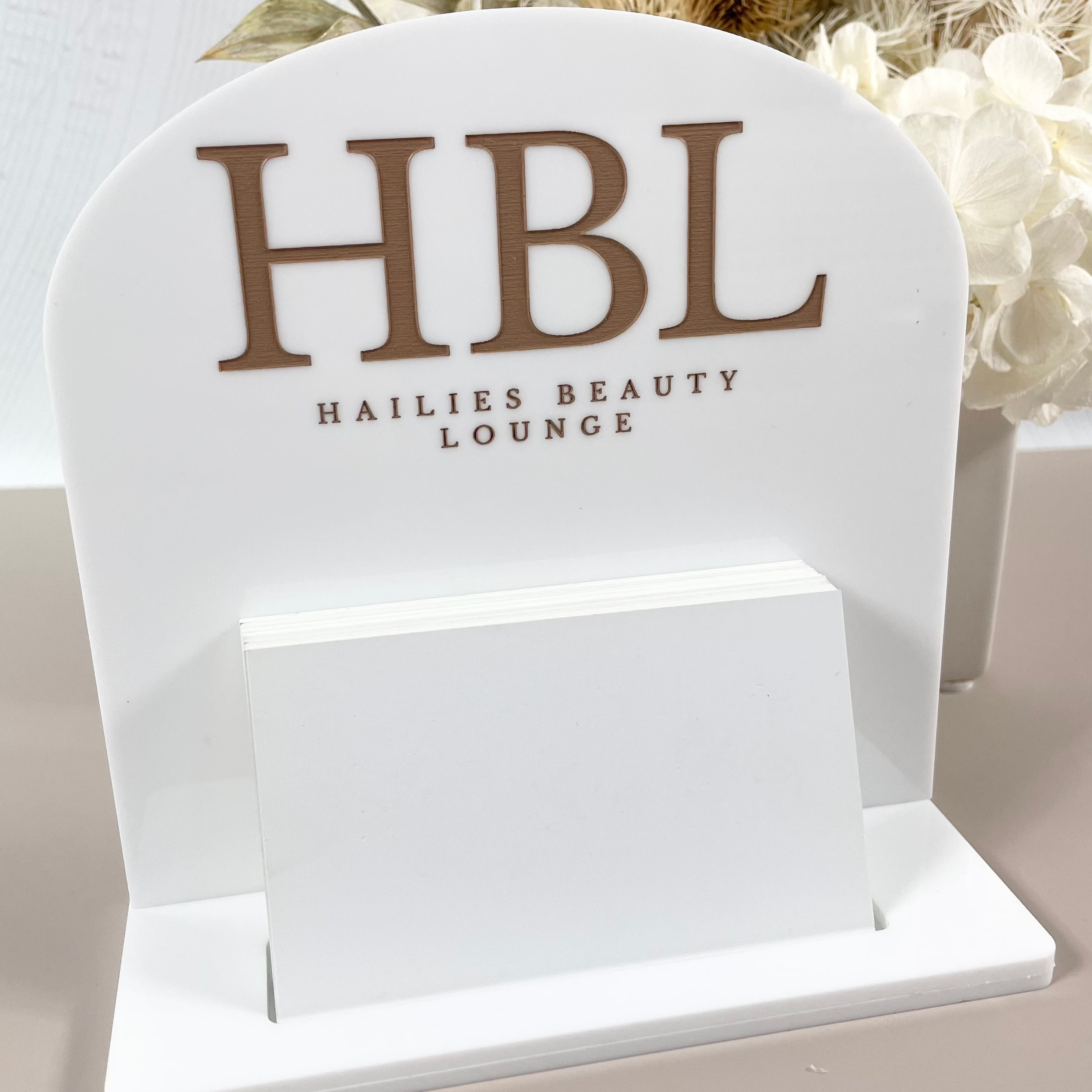 White business card holder with gold HBL branding for salon counters