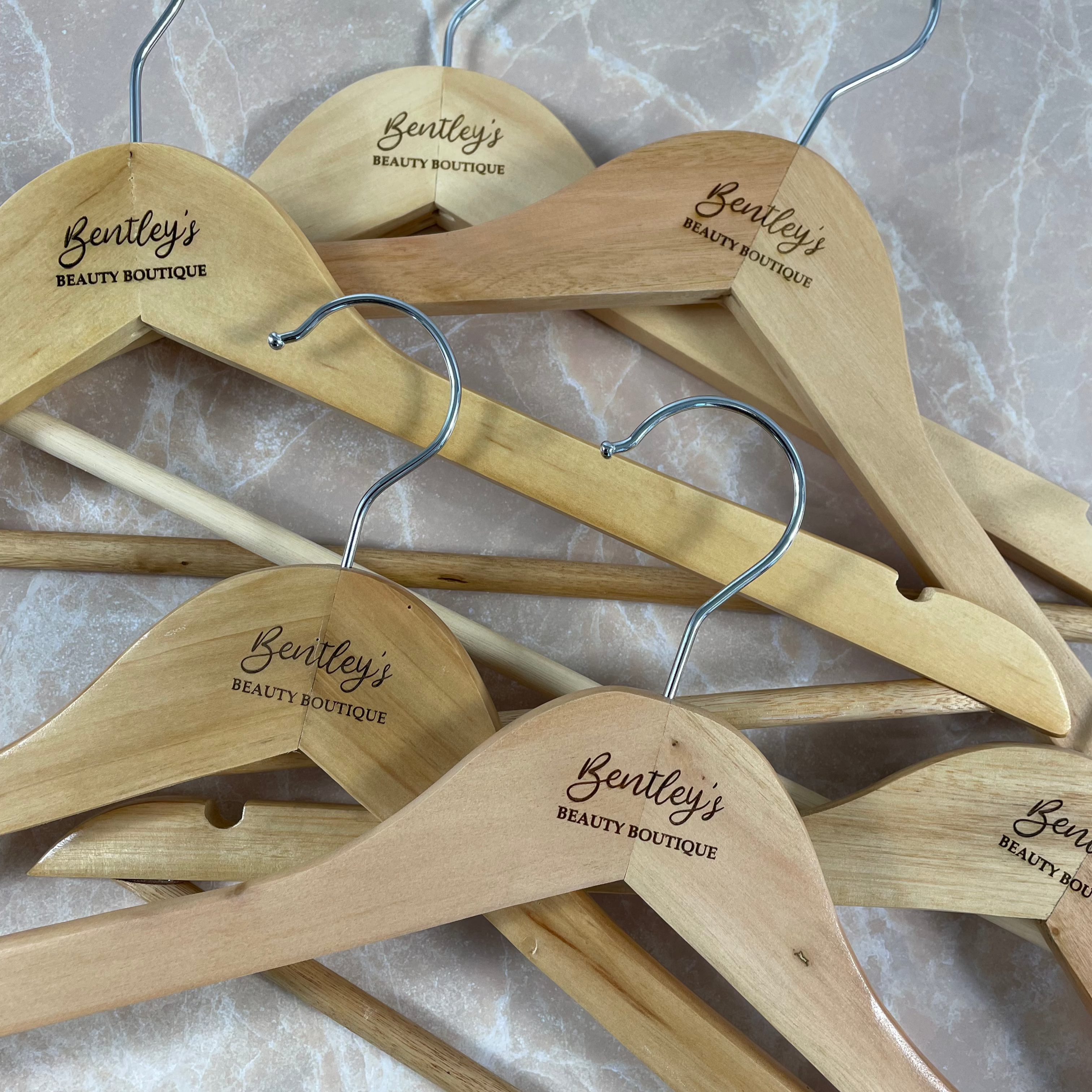 Set of engraved wooden coat hangers featuring custom business logos