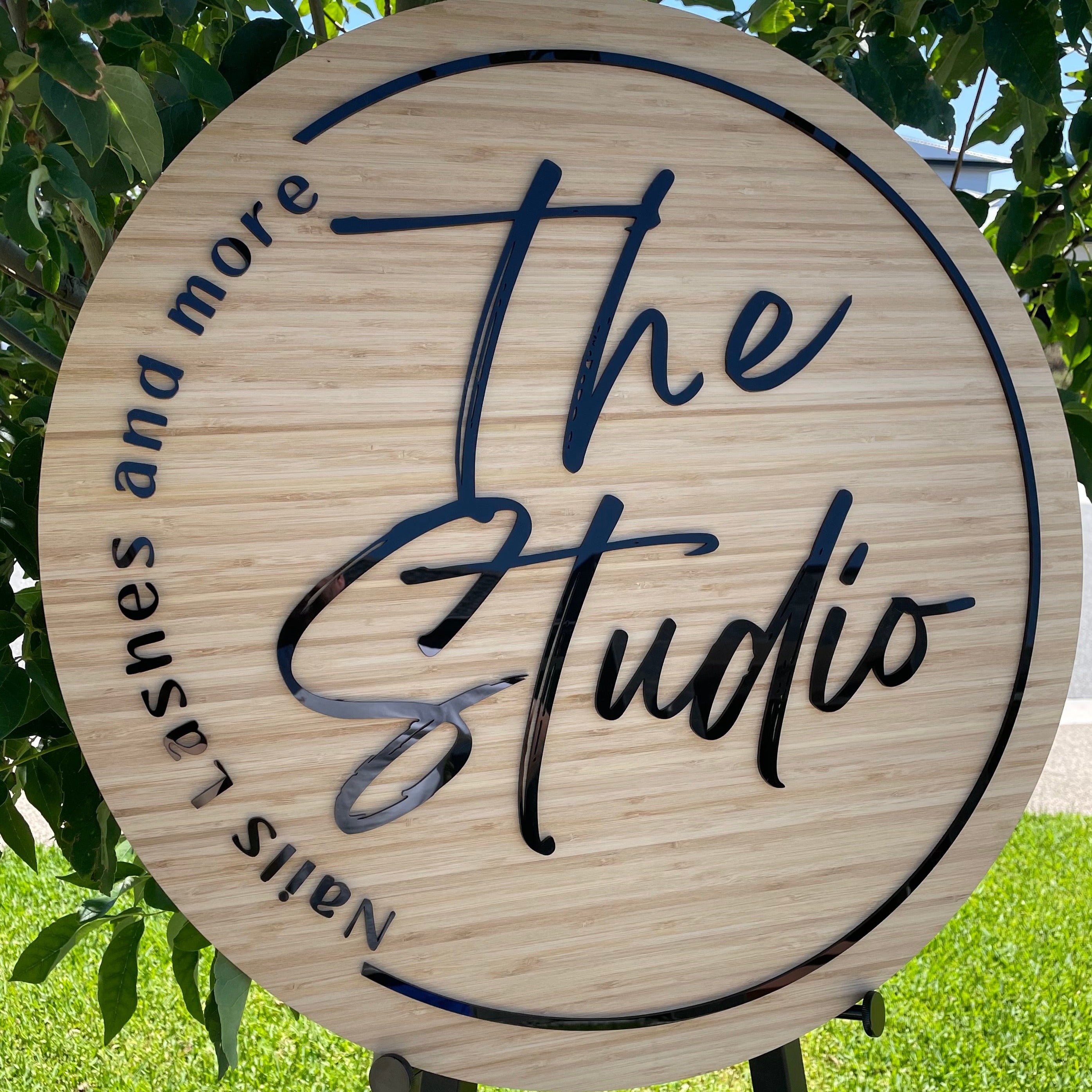 The Studio bamboo sign with black acrylic script and circular engraved detail