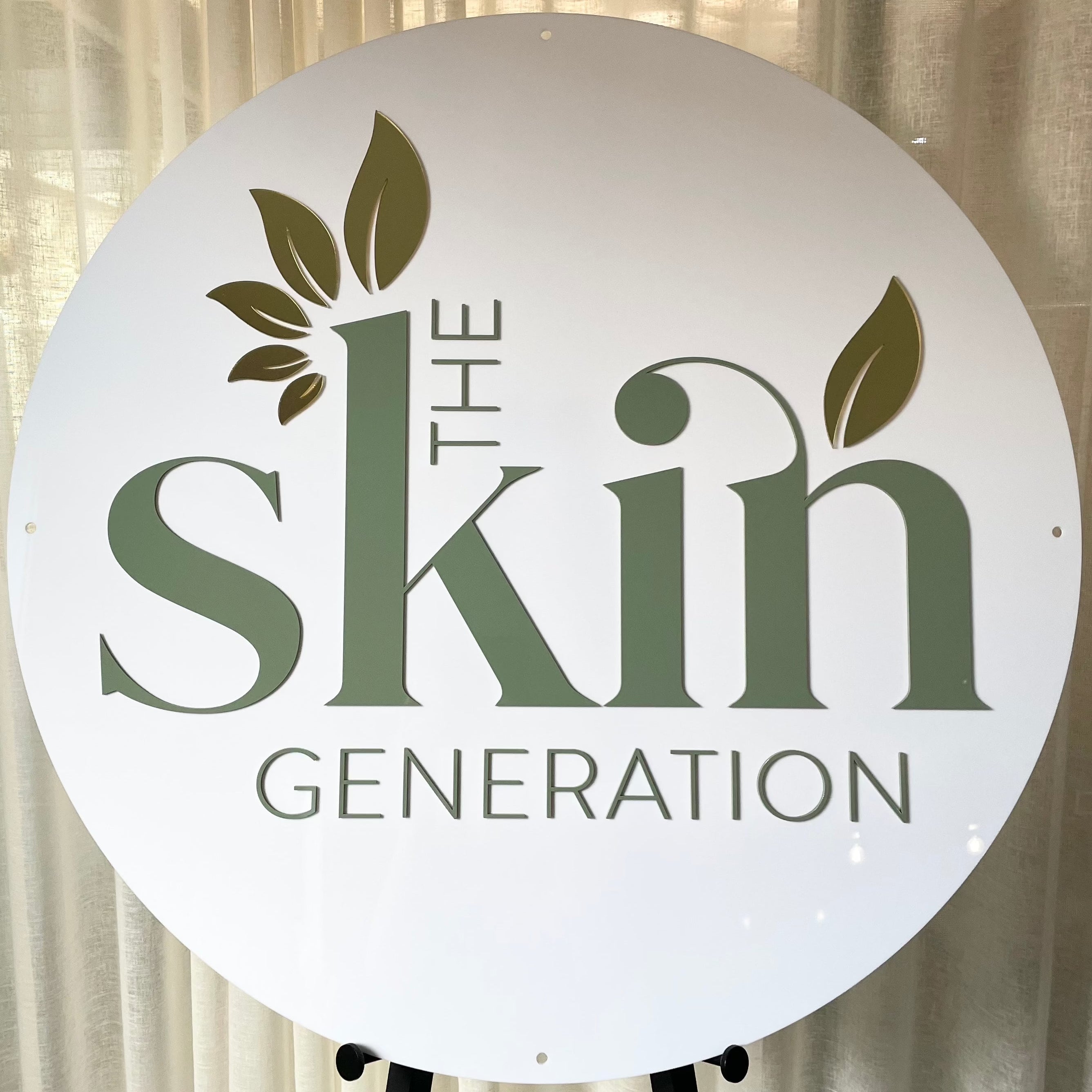 round white acrylic sign with green 3d letters. the skin generation