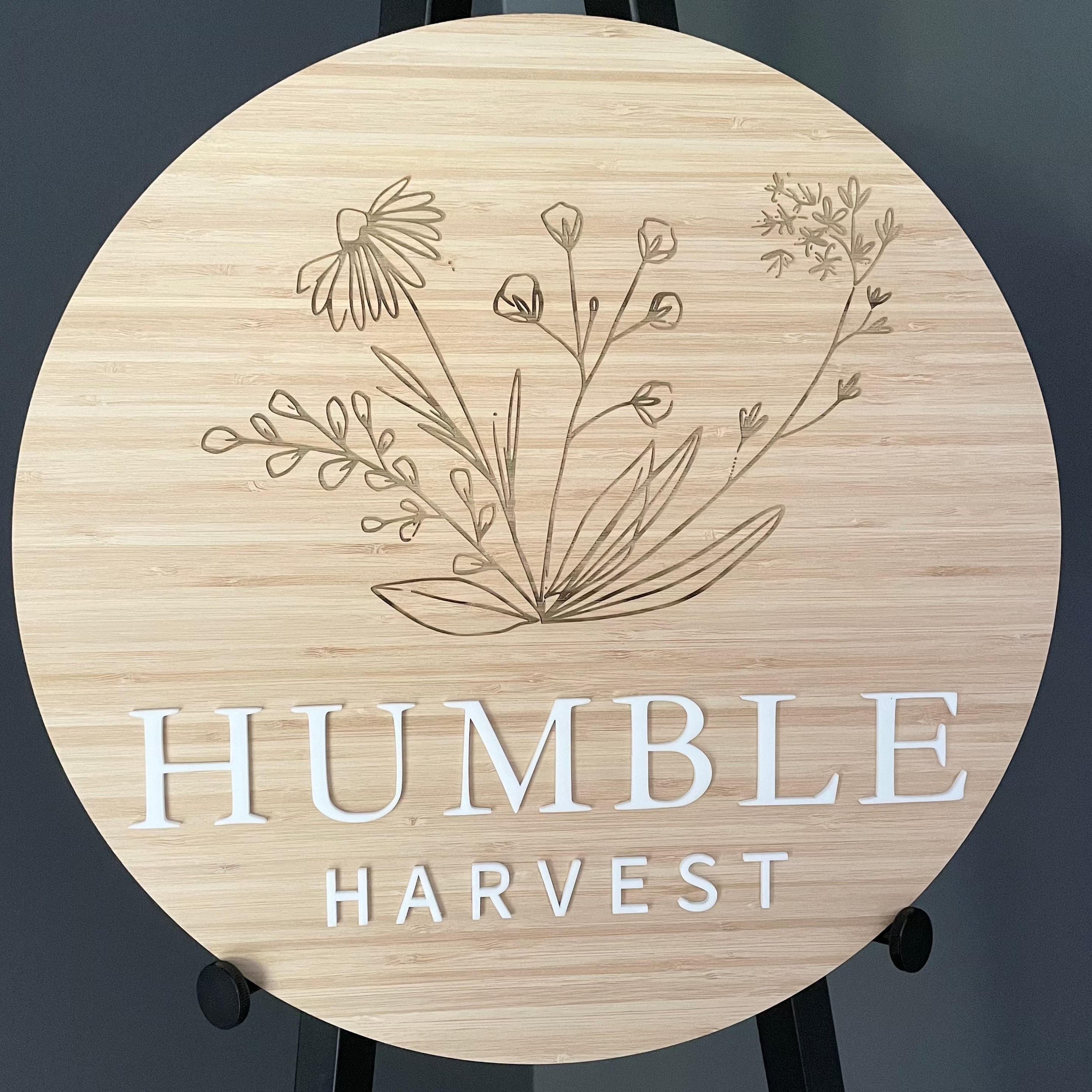 Humble Harvest bamboo sign with detailed flower line art and white acrylic brand name
