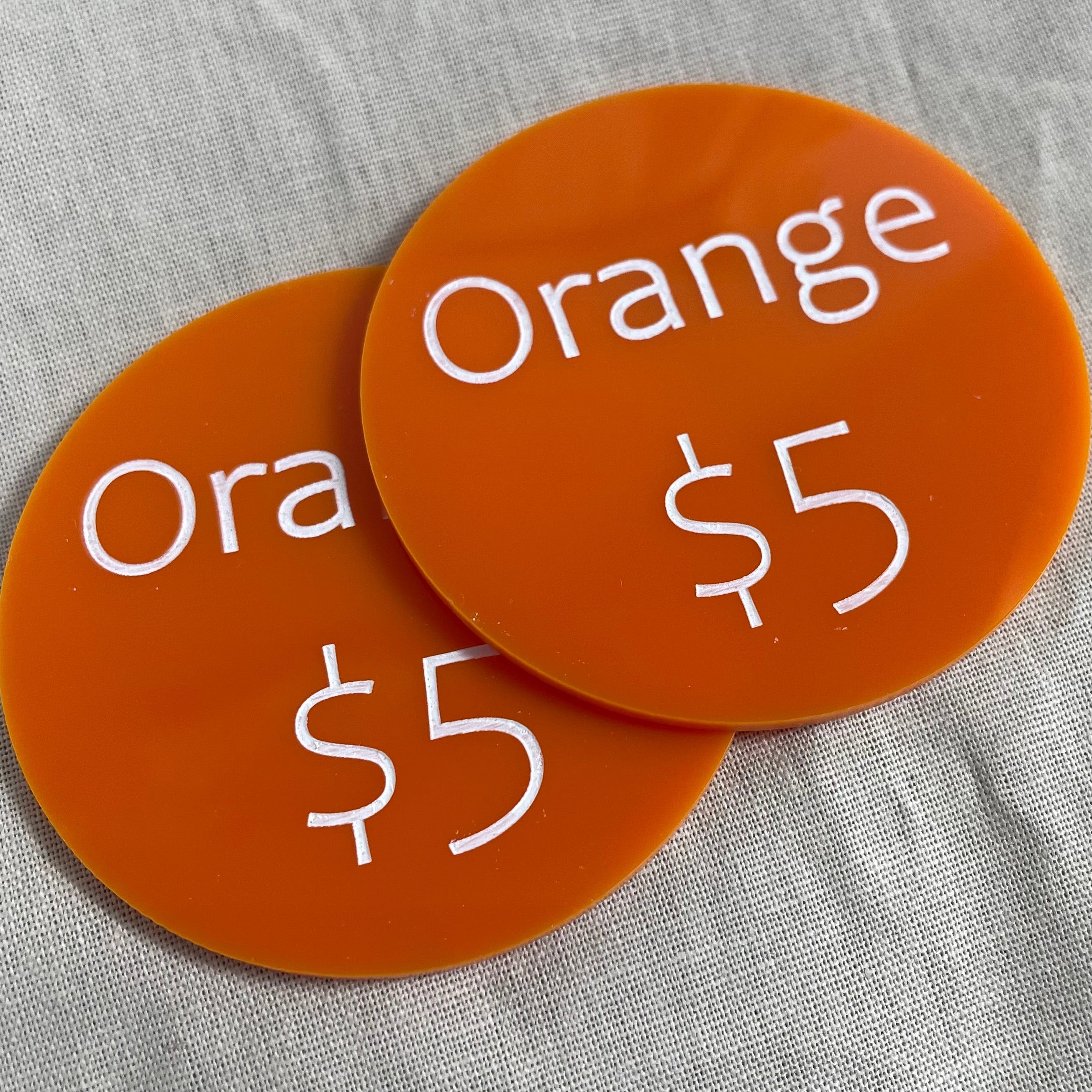 Orange acrylic price discs marked with product name and $5 price
