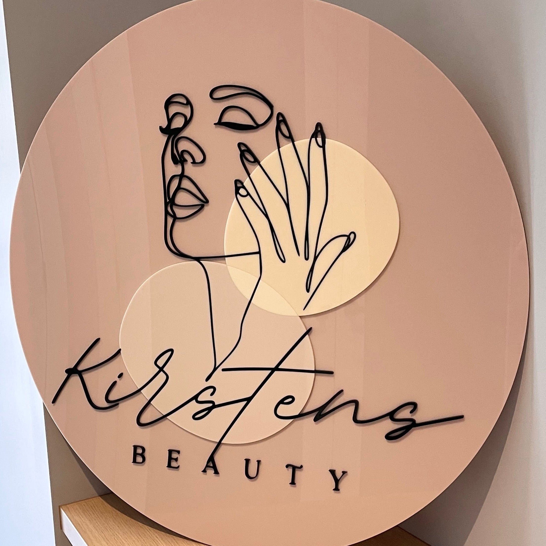 peach toned round acrylic business sign with line art and script. kristens beauty