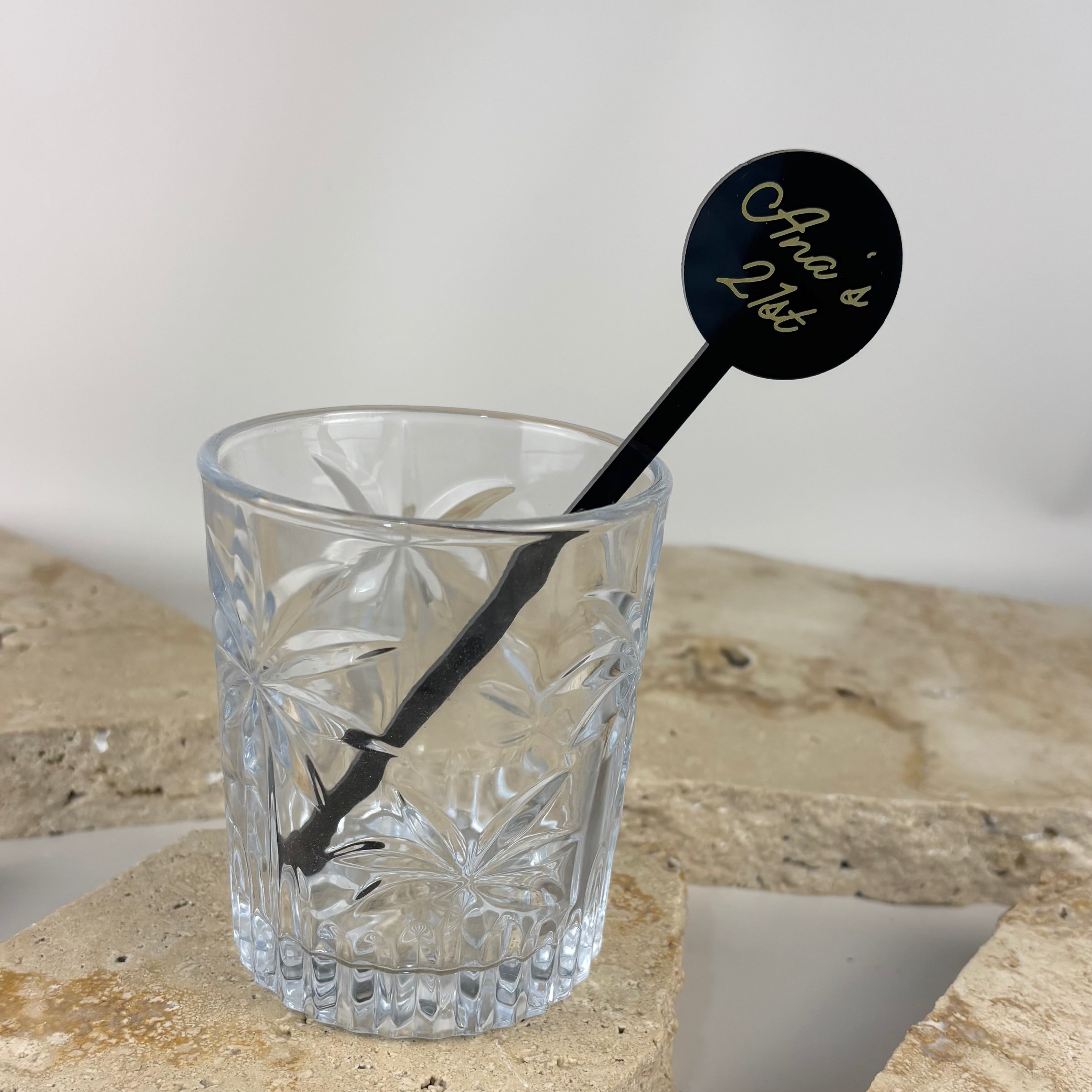 Custom black acrylic drink stirrer with personalised name, displayed in a cocktail glass, ideal for weddings, events, and bar styling.