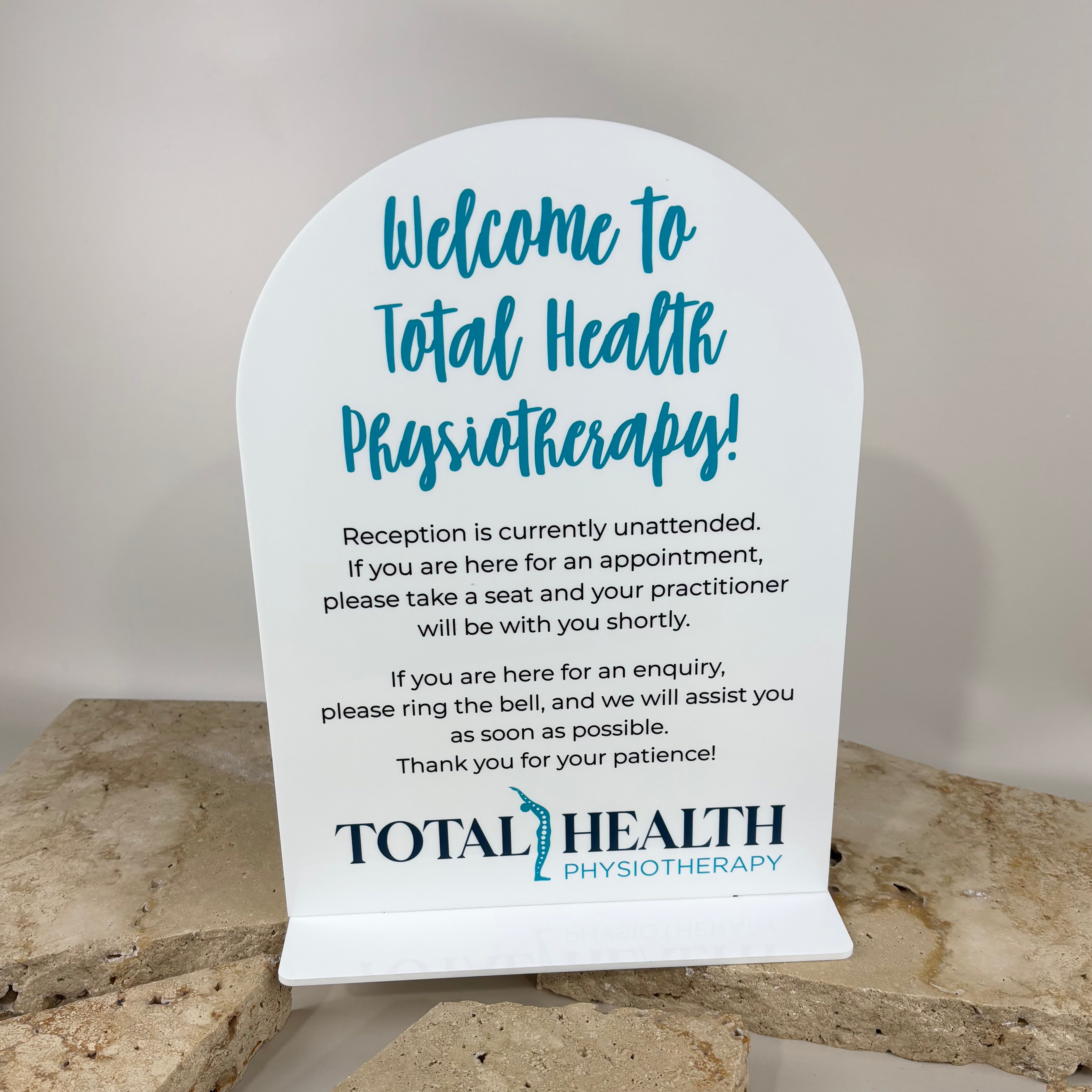 Custom acrylic reception sign for physiotherapy clinic with printed welcome message and business branding, professional countertop display stand used for clinic reception desks to guide patients and visitors.