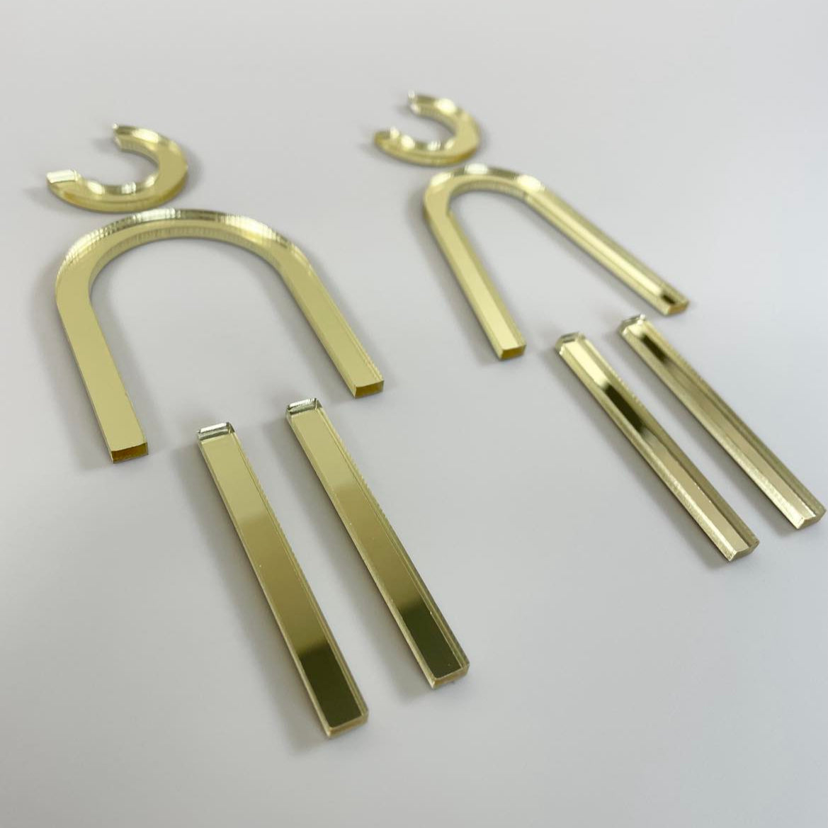 Set of gold male and female toilet signs laid flat, modern restroom signage for businesses