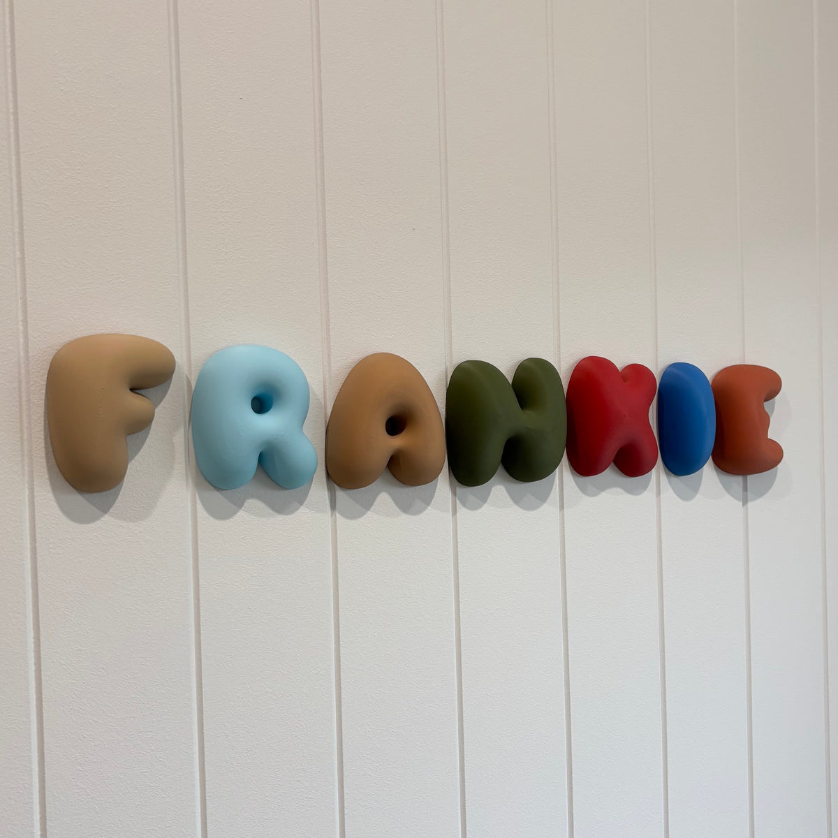 Custom 3D bubble name wall sign spelling “Frankie” in colourful rounded letters, mounted on a white panelled 