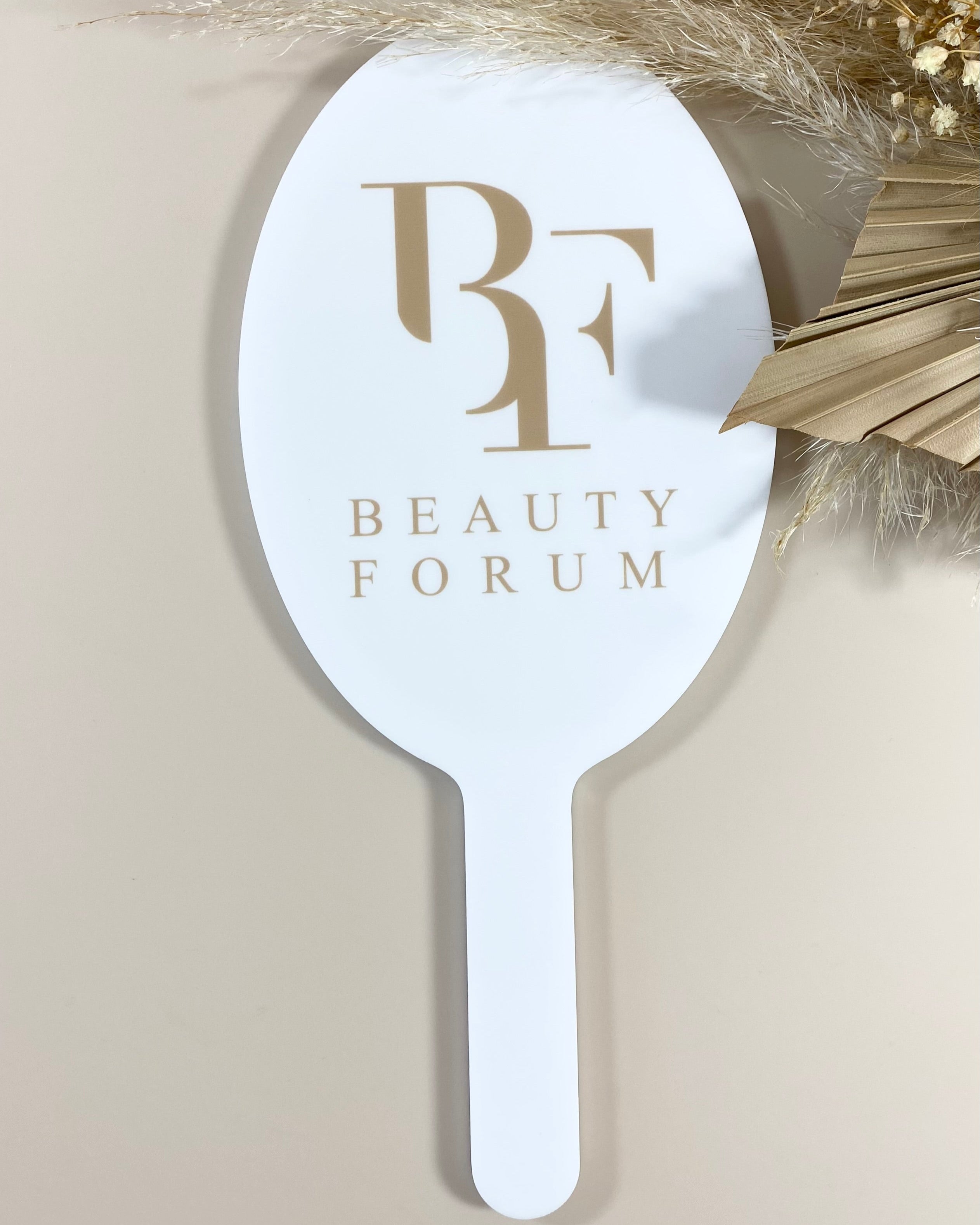 Branded oval handheld mirror with Beauty Forum logo on white handle