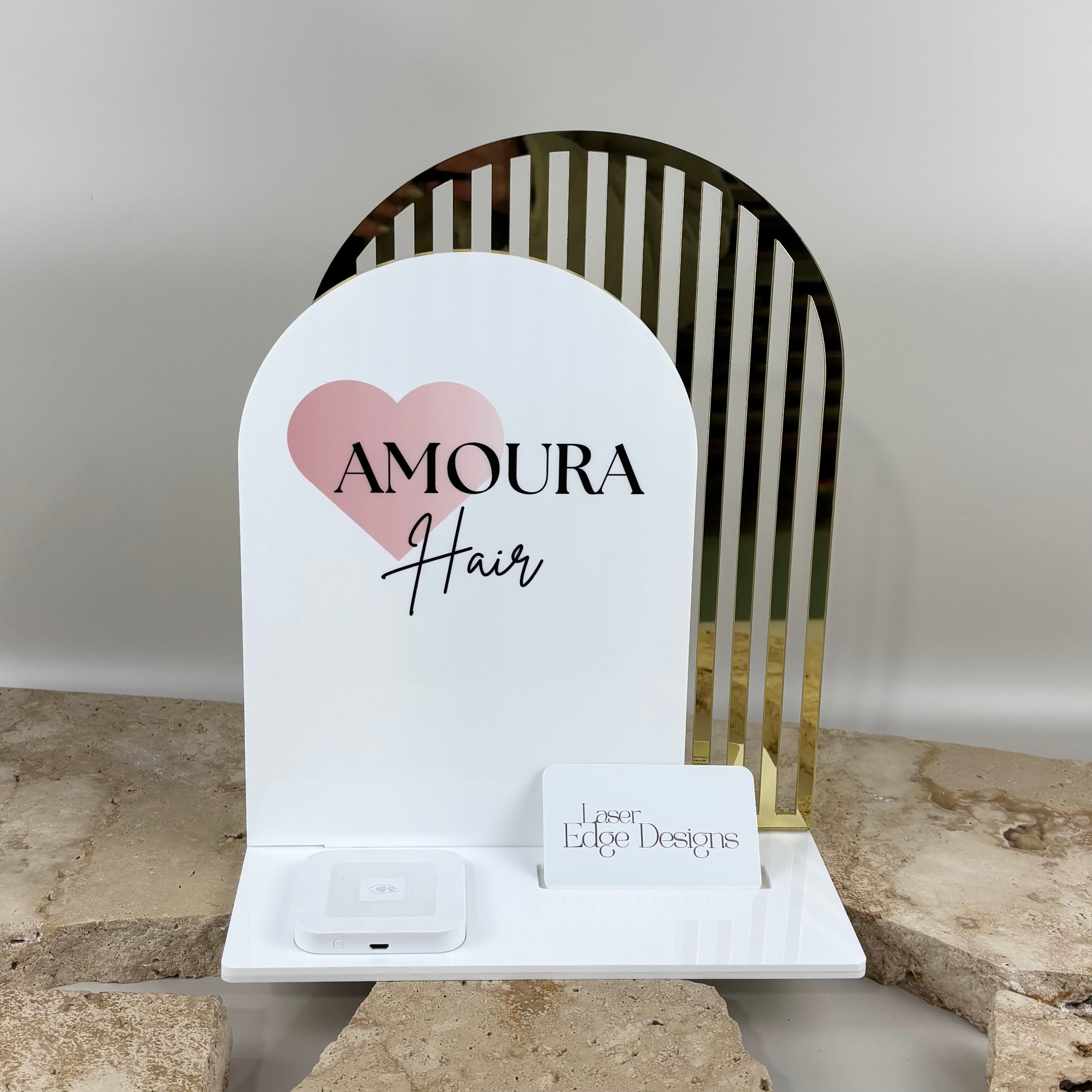 Custom acrylic business counter stand for Amoura Hair with UV printed logo, gold mirror arch detail, Square reader dock and business card holder.