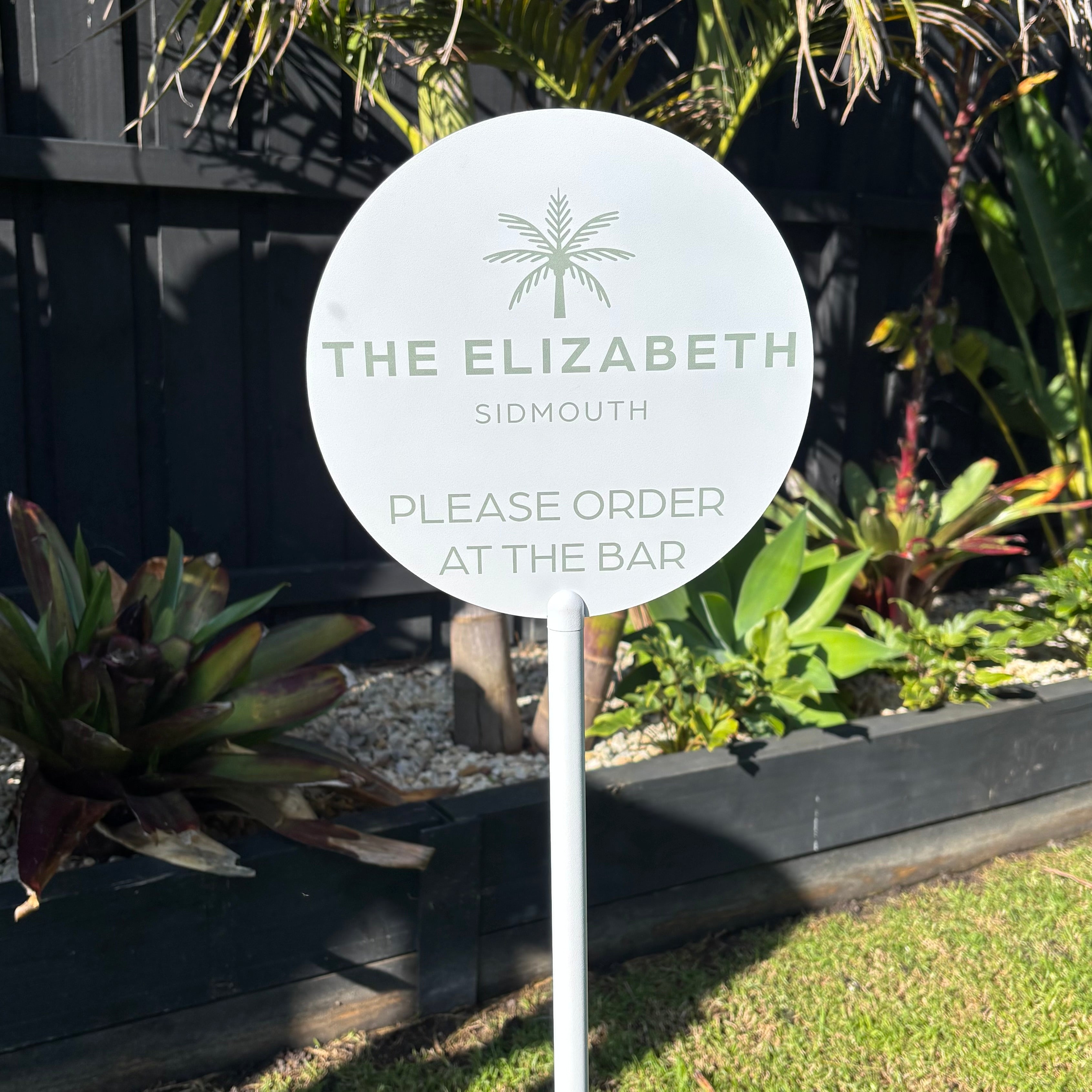 Custom round outdoor hospitality sign on white powder coated post with UV printed logo and ‘Please Order at the Bar’ message for hotels, pubs, cafés, restaurants, beer gardens, resorts and outdoor dining areas.