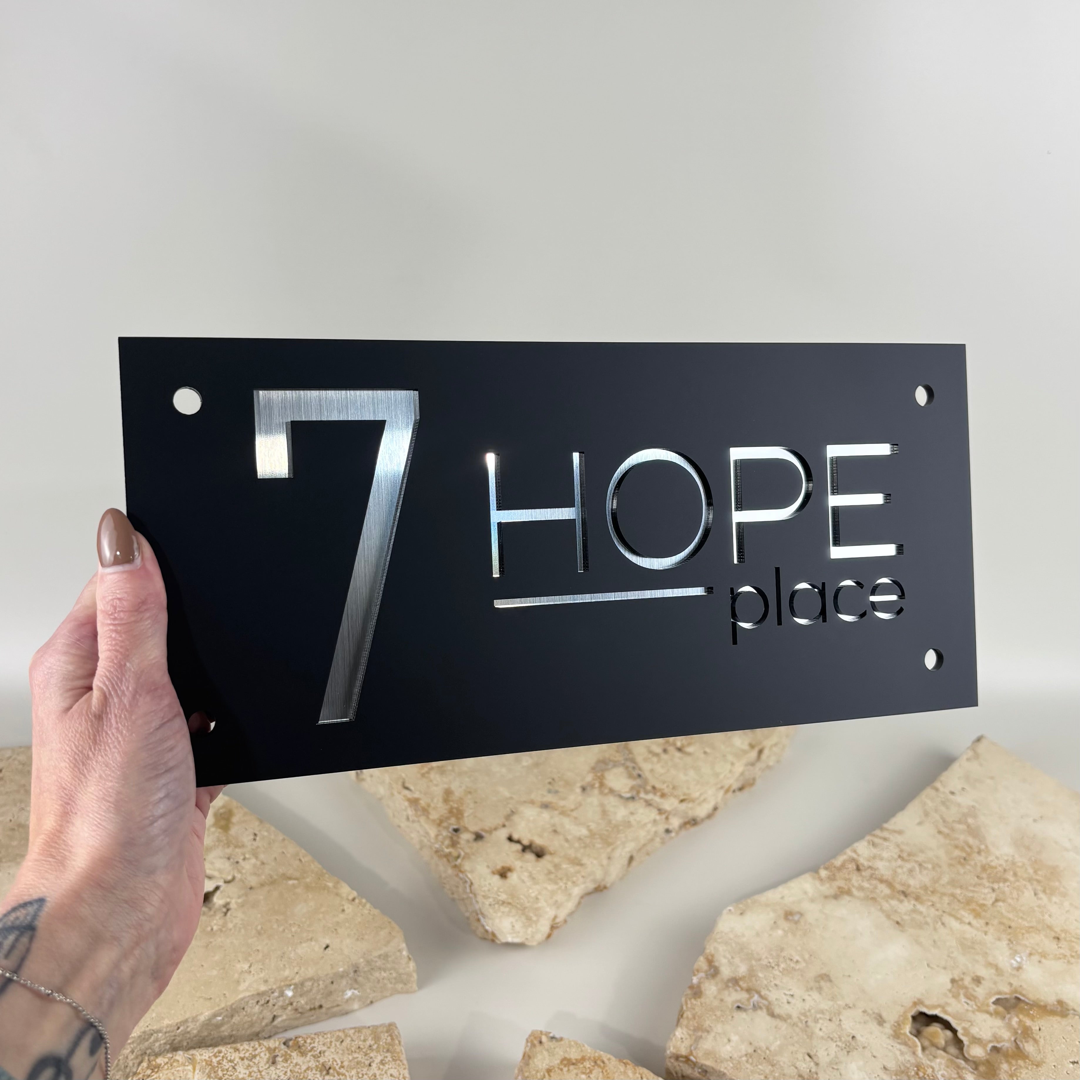 Custom black acrylic house number sign with brushed silver mirrored acrylic lettering, modern address plaque, laser cut outdoor house signage, contemporary property number sign, weather-resistant acrylic address plate for home entrance and street identification.