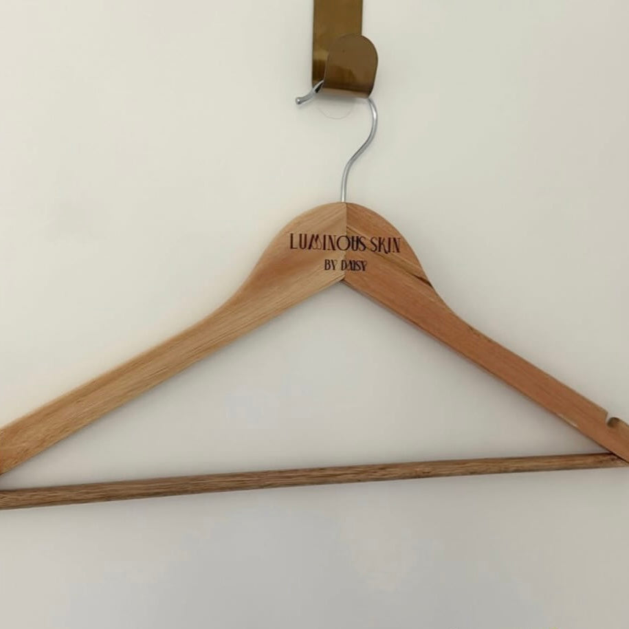 Custom engraved timber hanger with business logo branding for beauty salons and skin clinics, personalised wooden coat hanger for aesthetic studios and client wardrobes