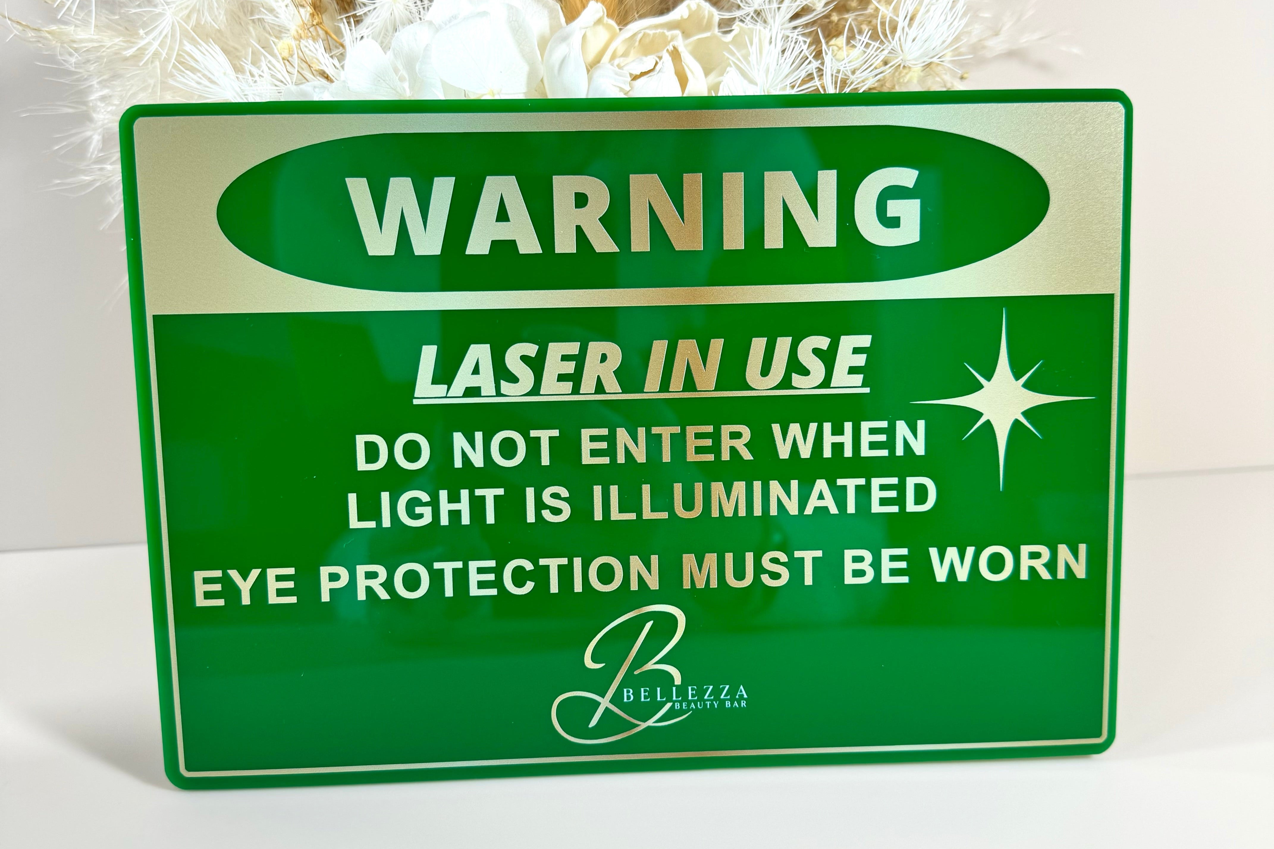 Green safety warning sign for laser treatment rooms, includes eye protection notice.