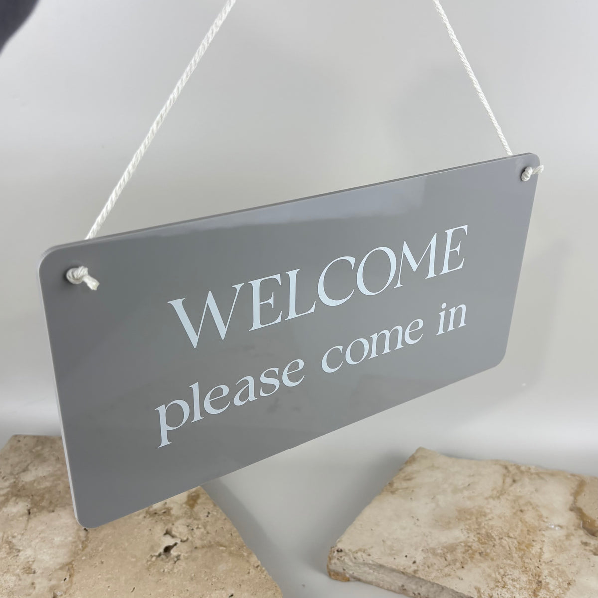 Custom grey acrylic welcome hanging door sign with white lettering and rope, ideal for salons, beauty rooms, clinics and small businesses.