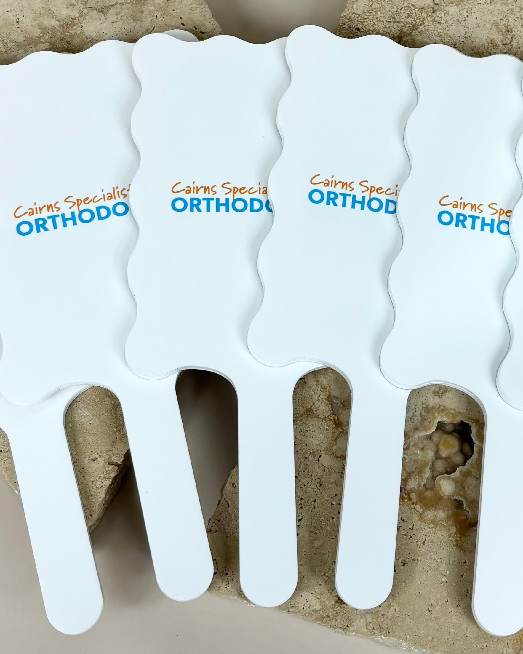 Set of blue wavy handheld mirrors with orthodontic clinic branding
