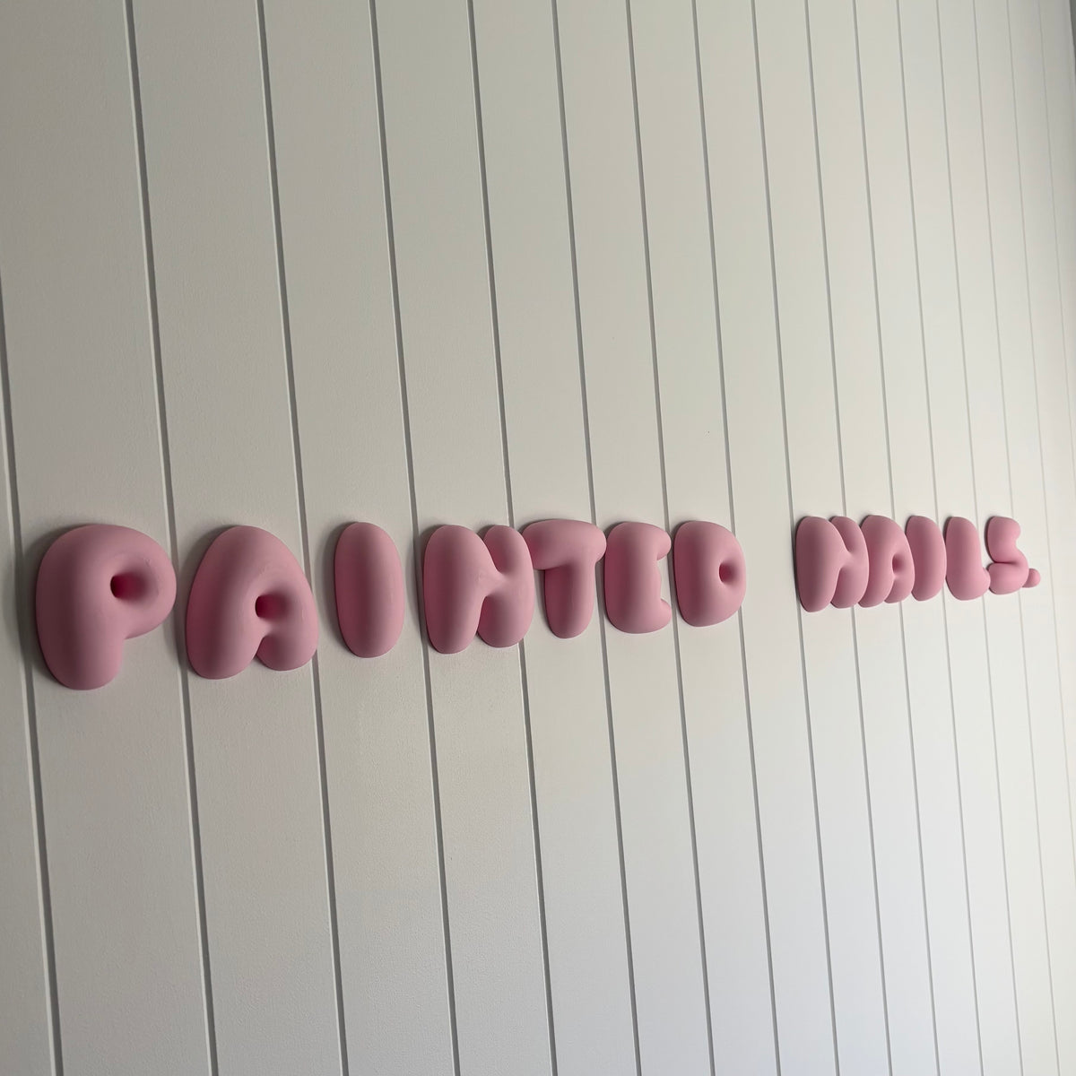  Pink 3D bubble lettering wall sign for a nail salon or beauty business, featuring raised custom letters mounted on a white panelled wall.