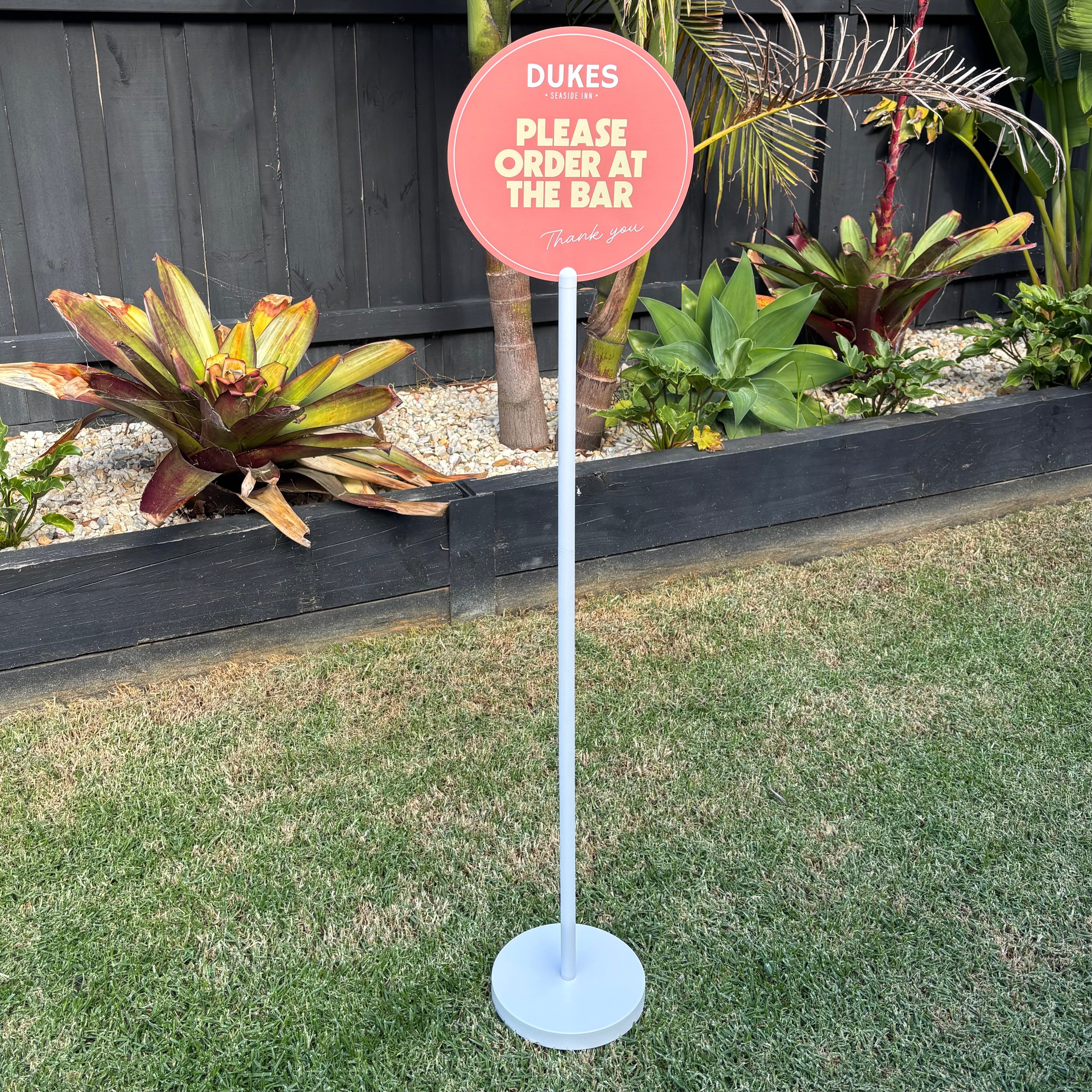 Custom round acrylic floor sign stand for restaurants Australia, coral “please order at the bar” signage on freestanding pole display