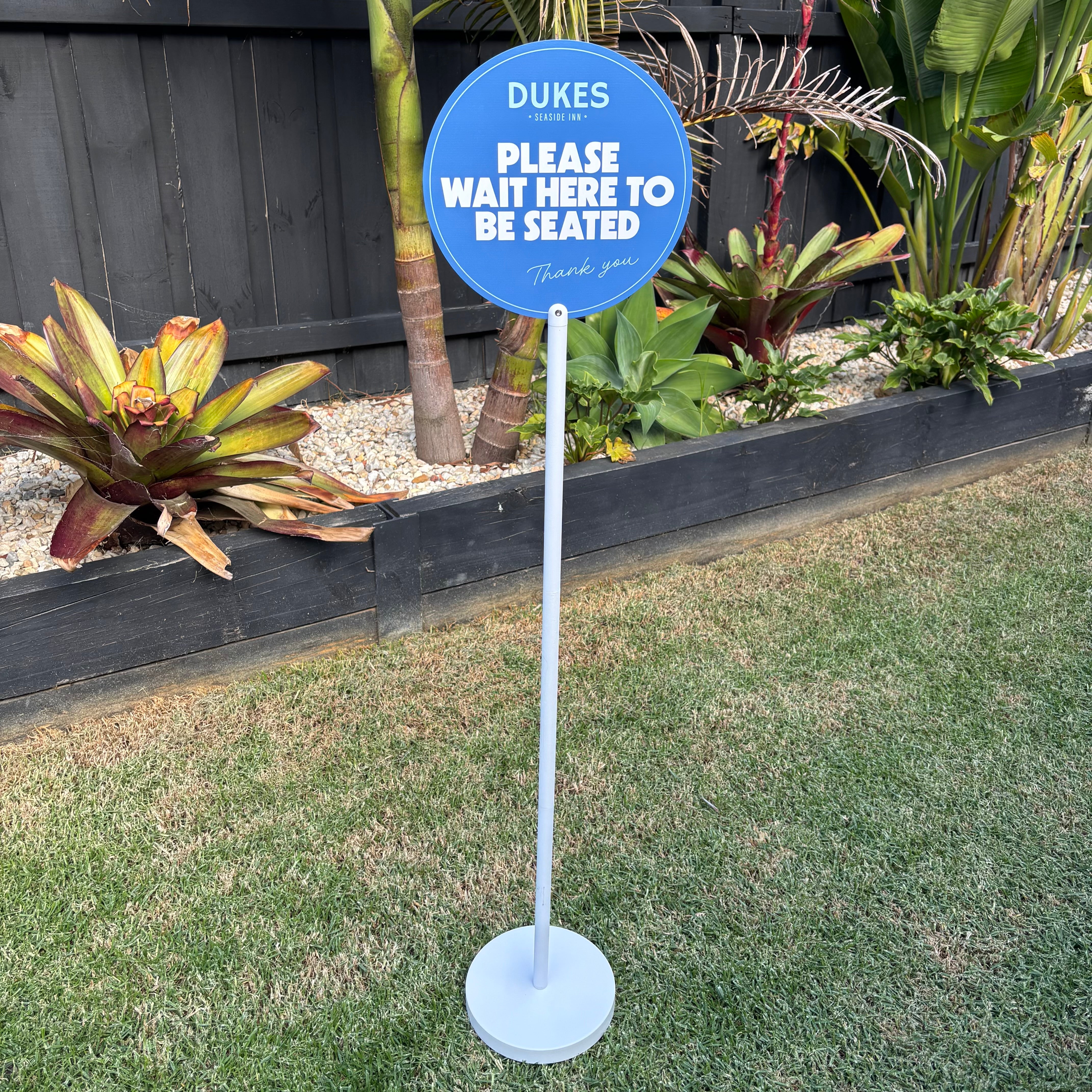 Blue round acrylic floor sign stand “please wait here to be seated” custom business signage Australia with freestanding base