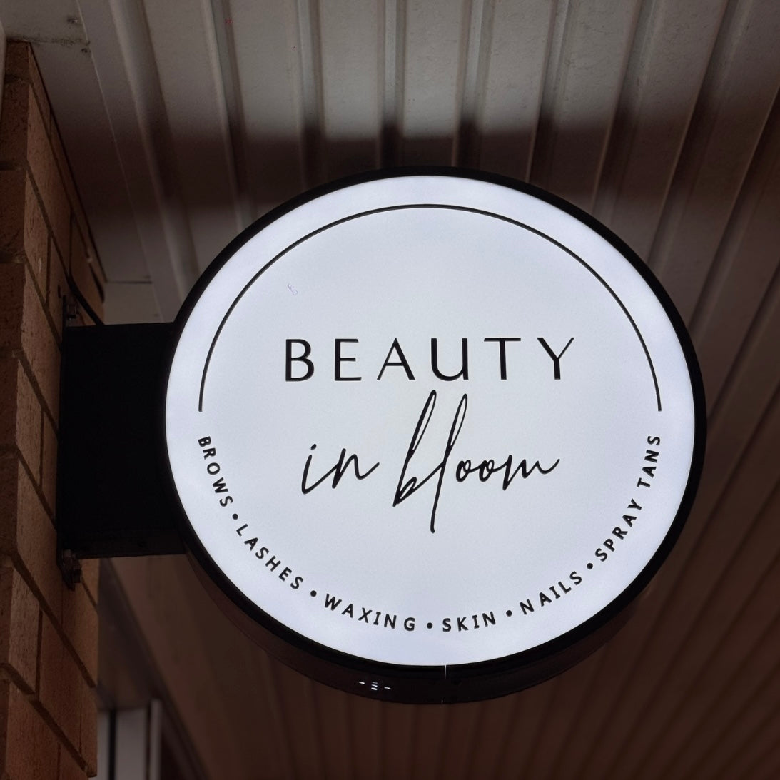 Custom LED light box blade sign for beauty salons, illuminated round business sign with black and white branding for lashes, brows, skin clinics and nail salons in Australia