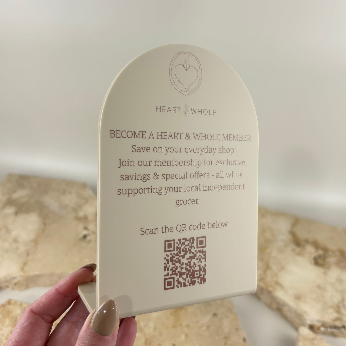 Custom cream acrylic arch countertop sign featuring Heart & Whole branding, printed membership information and QR code for customer sign-ups at a retail store.