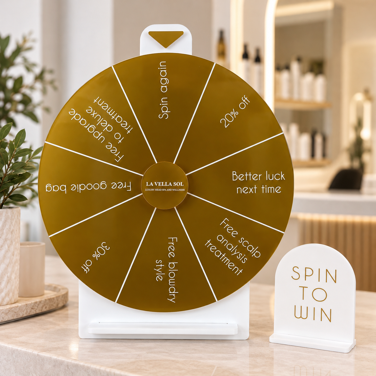 Custom gold acrylic Spin to Win prize wheel with personalised discounts and beauty treatment prizes, displayed on a modern salon reception counter with a matching sign.